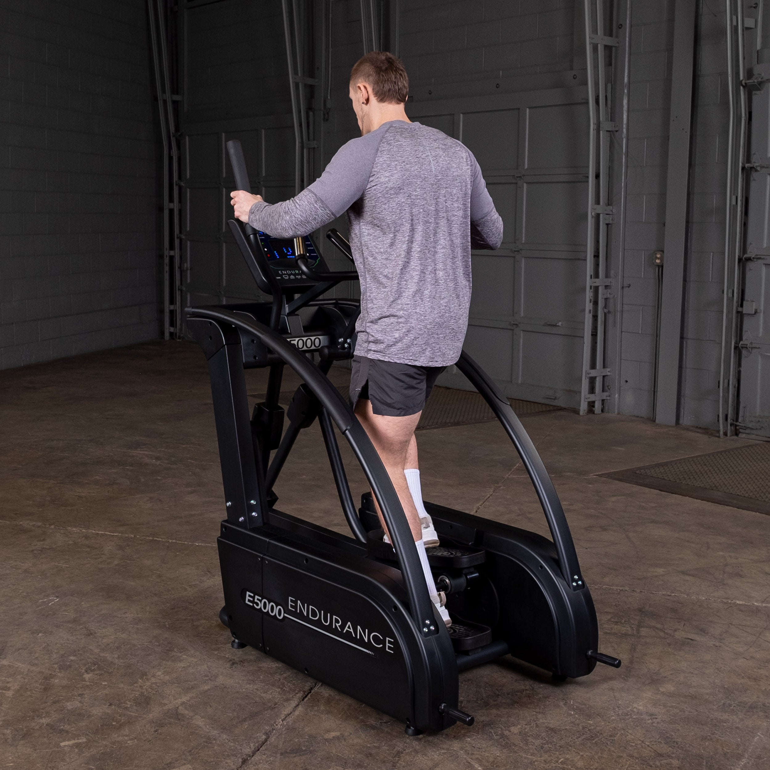 Man using Body-Solid Endurance E5000 elliptical trainer from rear view showing full body low impact workout