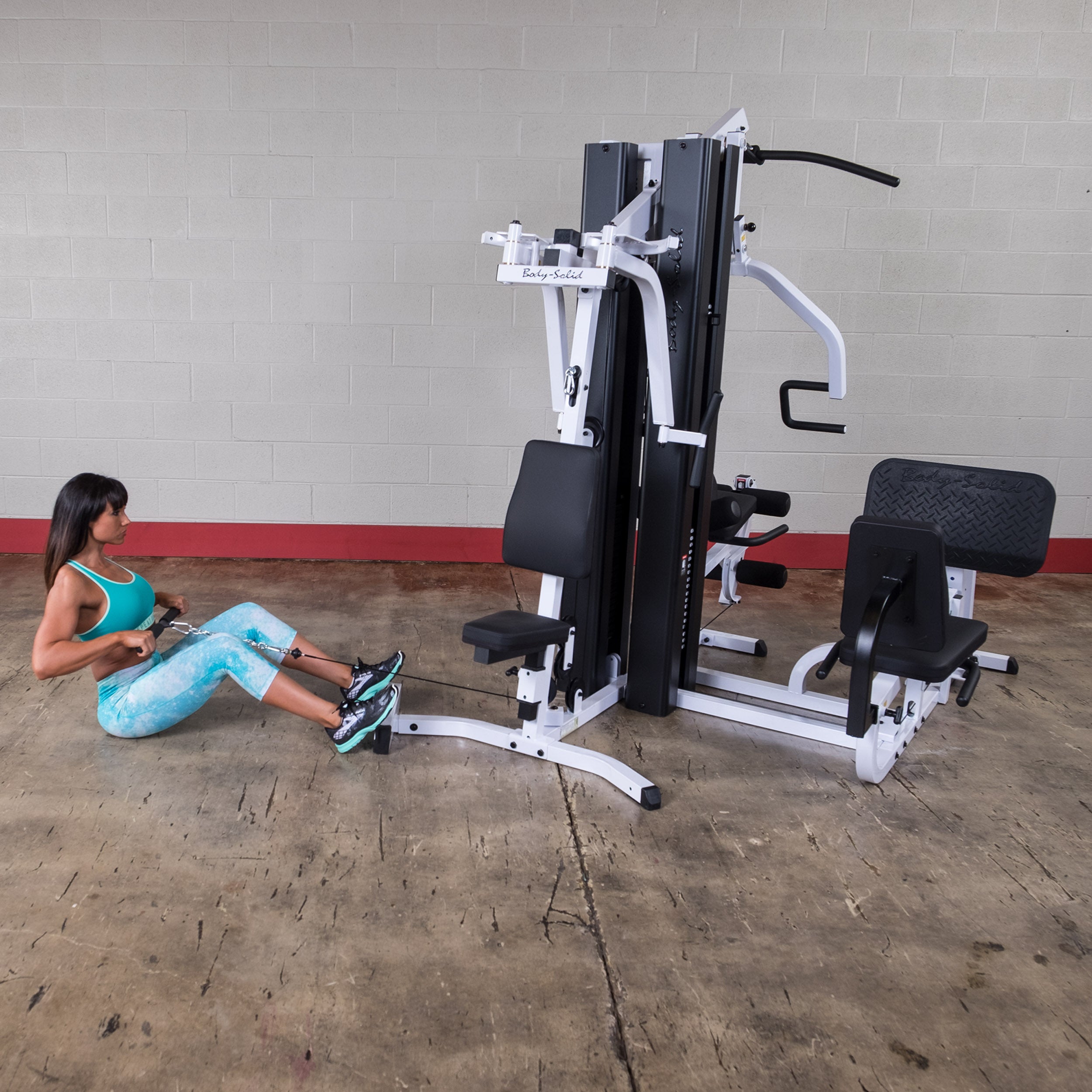 Person performing seated low row exercises on the Body-Solid EXM3000LPS dual stack multi-station gym