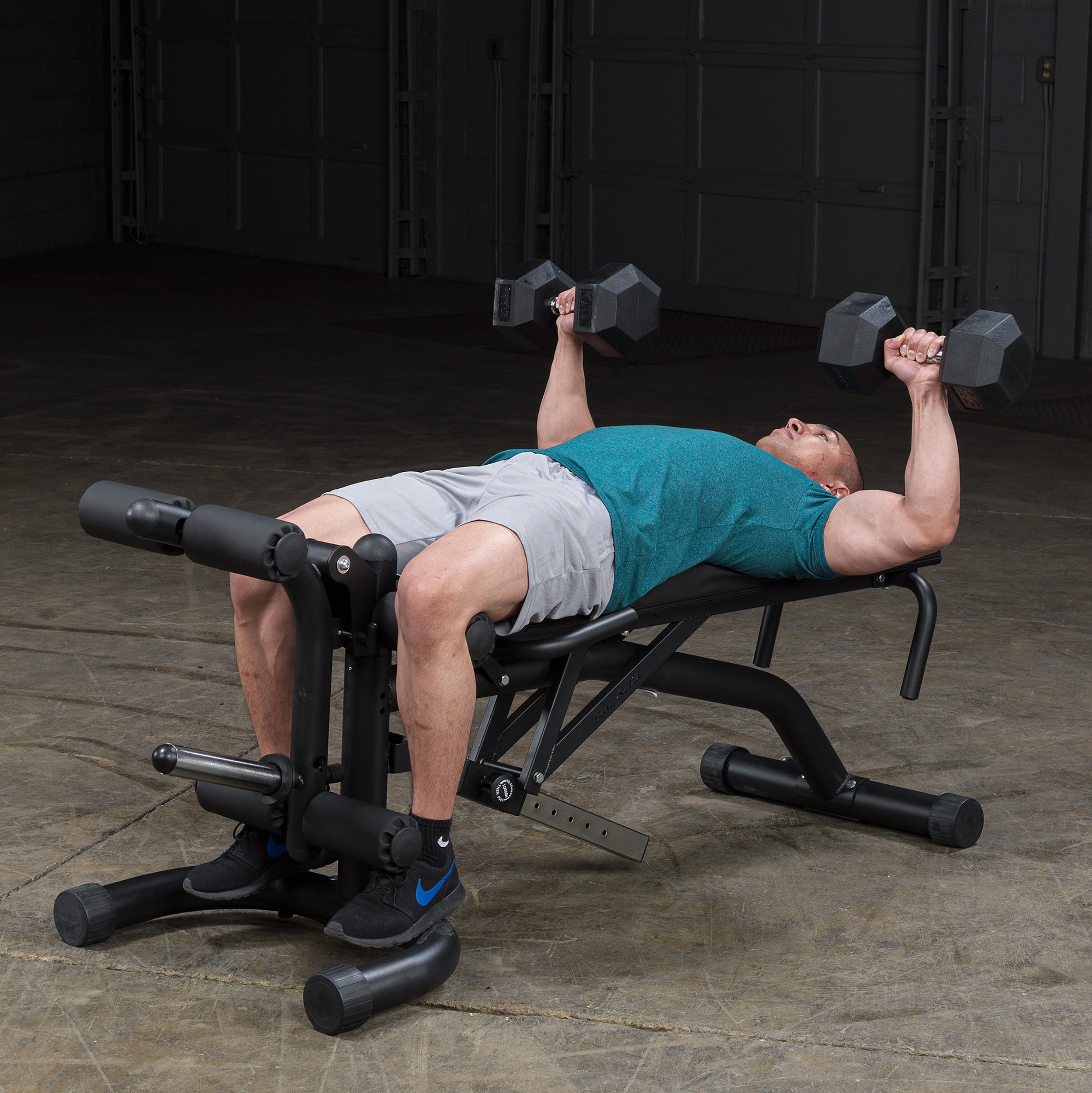 Person performing flat dumbbell bench press on the Body-Solid FID46 leverage flat incline decline bench