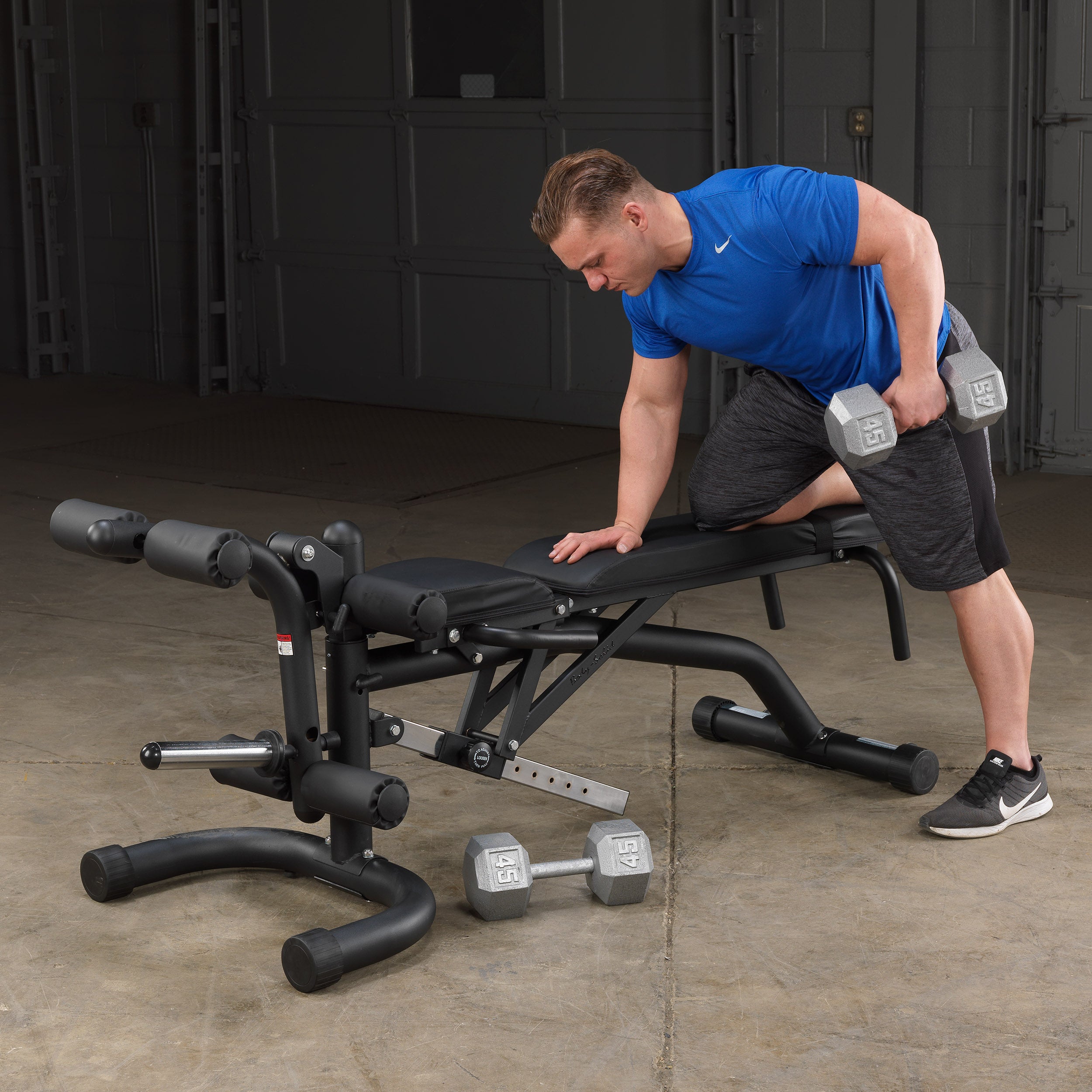 Person performing single-arm dumbbell rows using the Body-Solid FID46 leverage flat incline decline bench