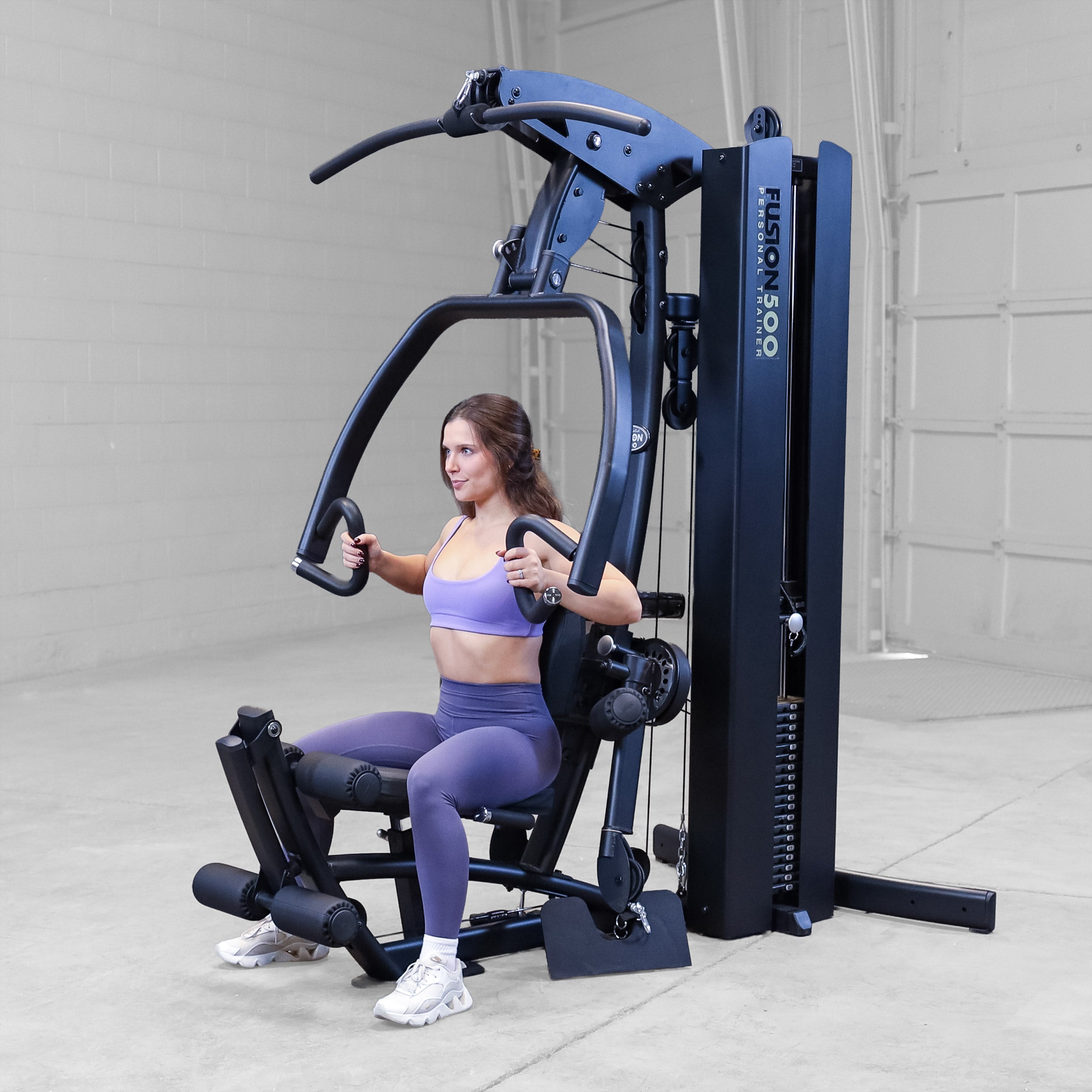 Person performing a chest press exercise on the Body-Solid Fusion 500B Personal Trainer using the articulating press arms and adjustable seat