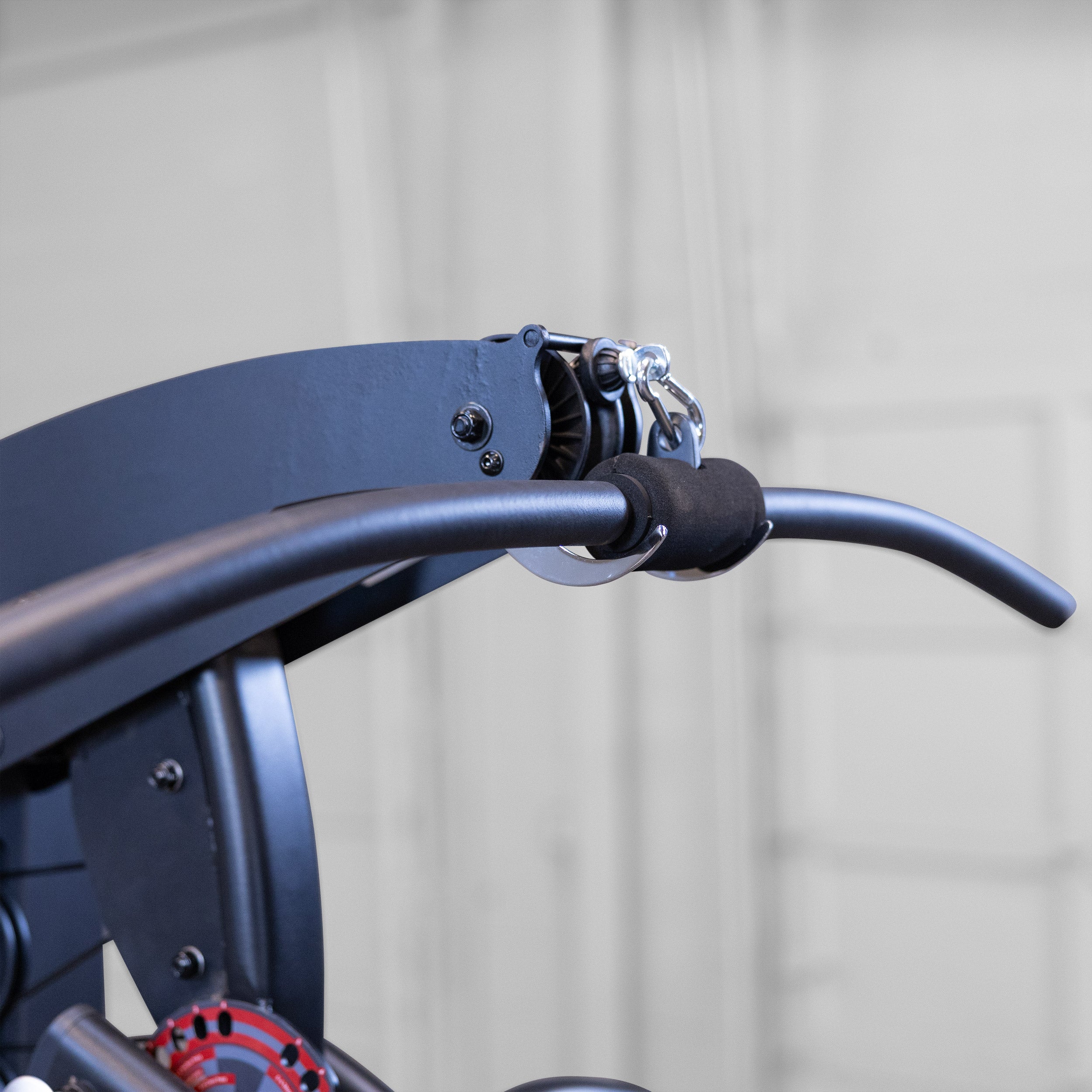 Close-up of the lat pulldown bar and high pulley on the Body-Solid Fusion 500B Personal Trainer showing the padded grip and cable attachment system