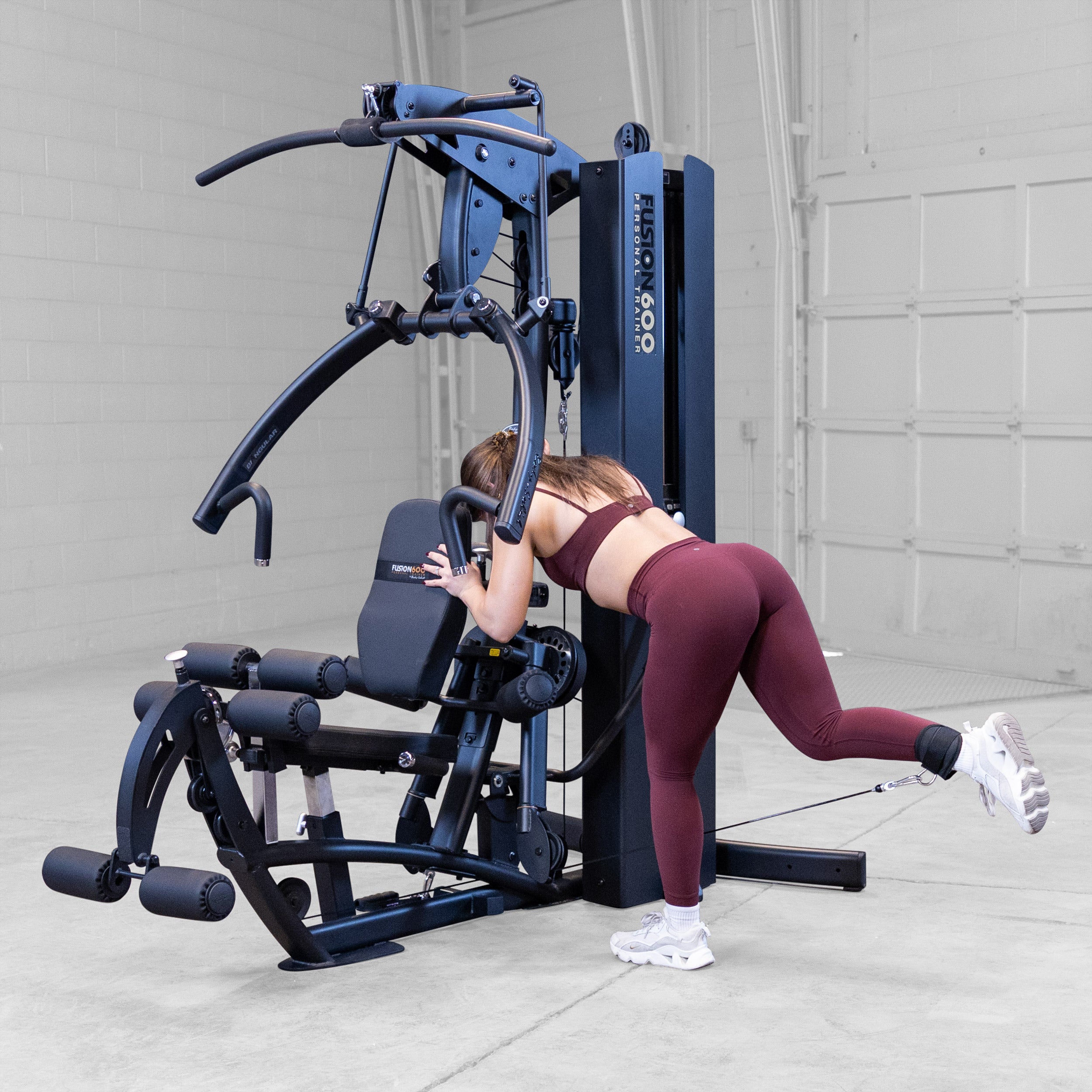 Woman performing a glute kickback on the Body-Solid Fusion 600B Personal Trainer using an ankle strap attachment