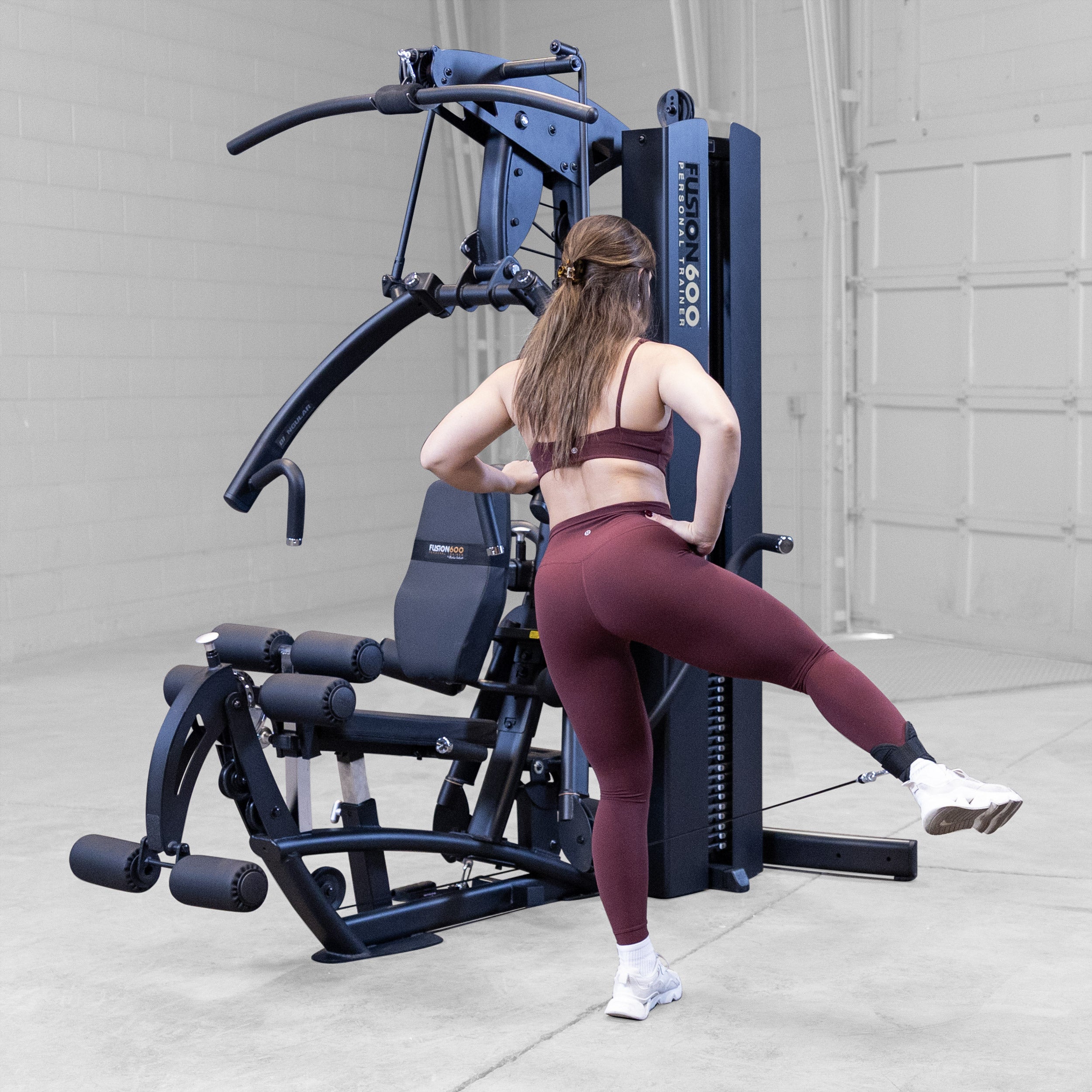 Woman performing a standing hip abduction on the Body-Solid Fusion 600B Personal Trainer using an ankle strap attachment