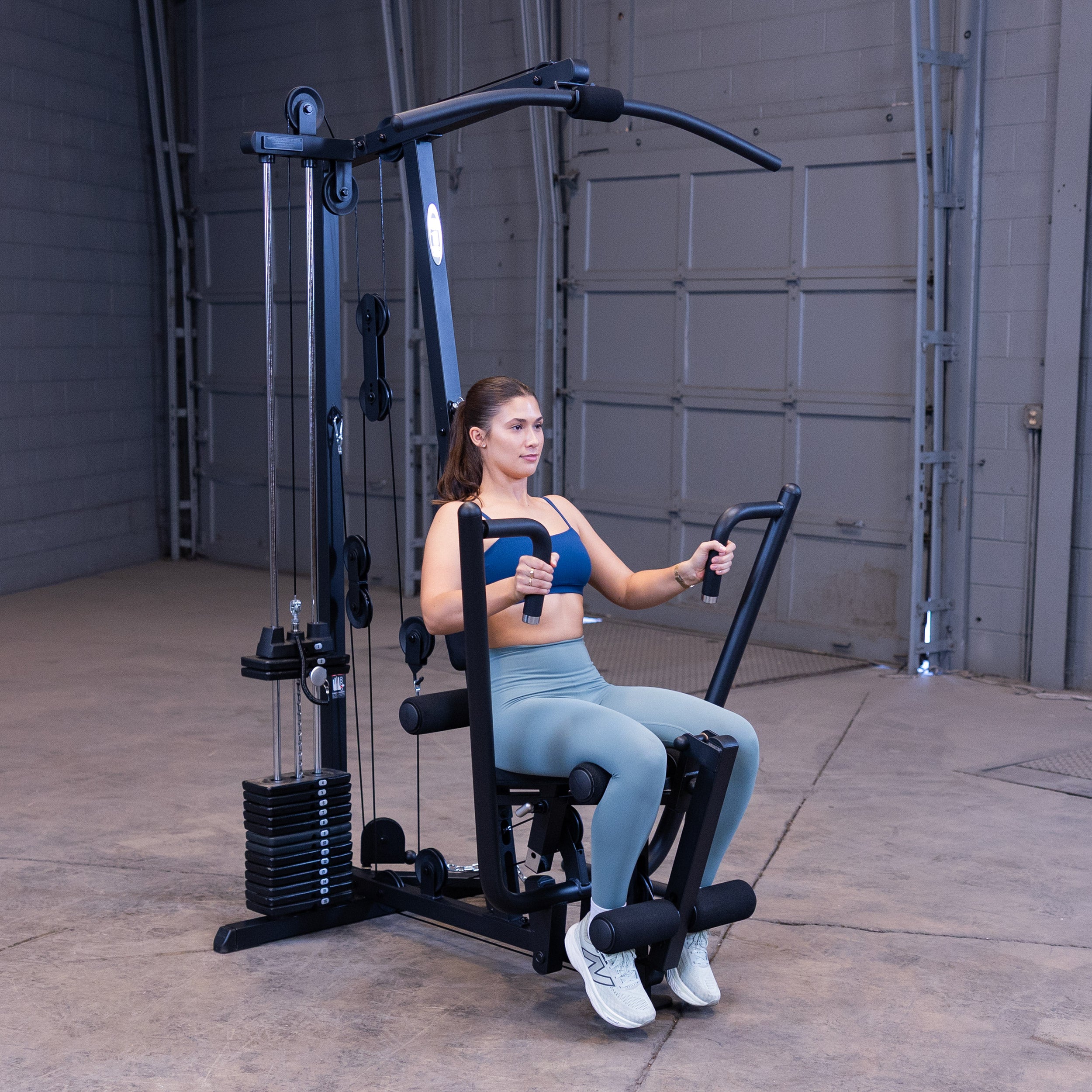 Person performing chest presses on the Body-Solid G1B multi station home gym to strengthen the chest shoulders and triceps