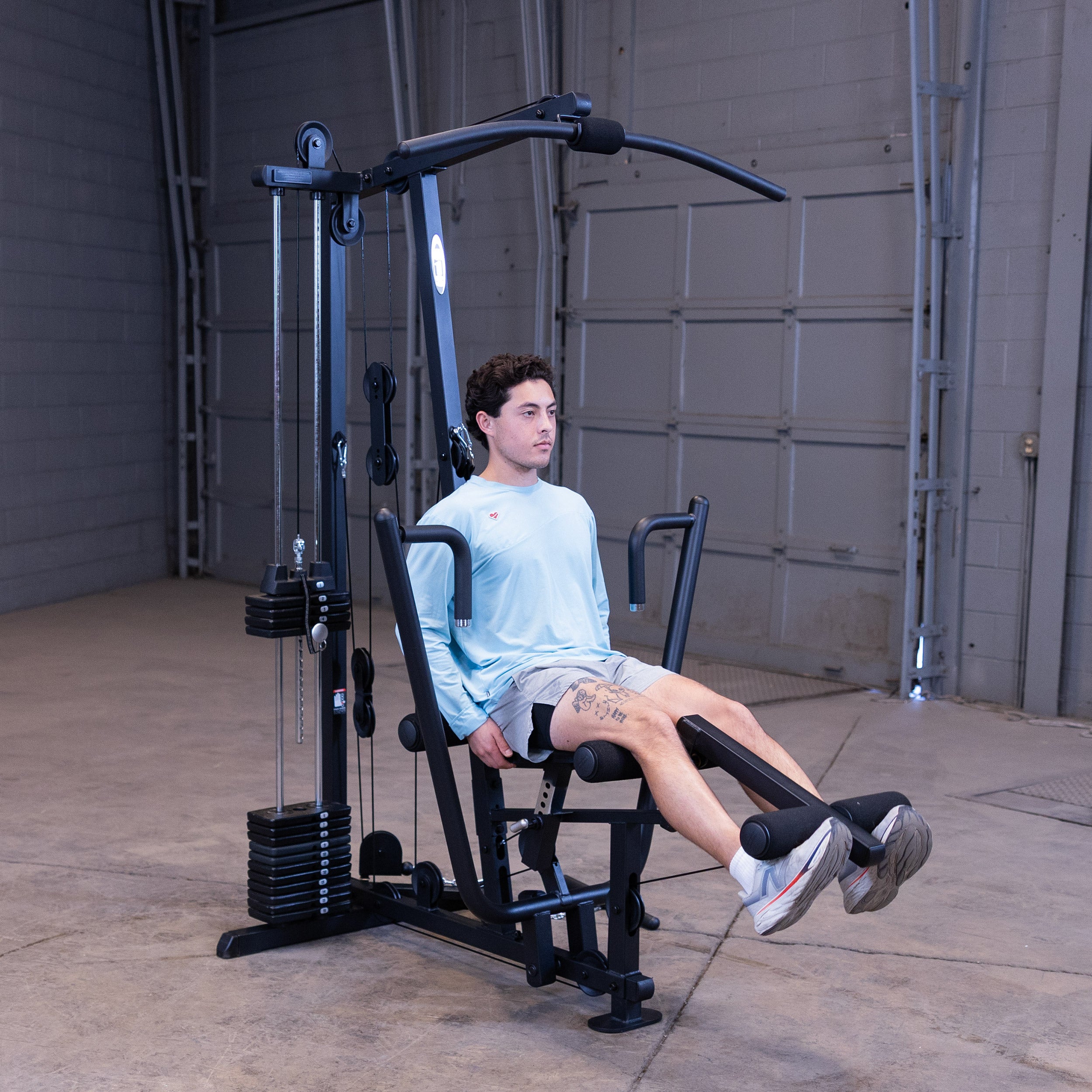 Person performing leg extensions on the Body-Solid G1B multi station home gym to strengthen the quadriceps