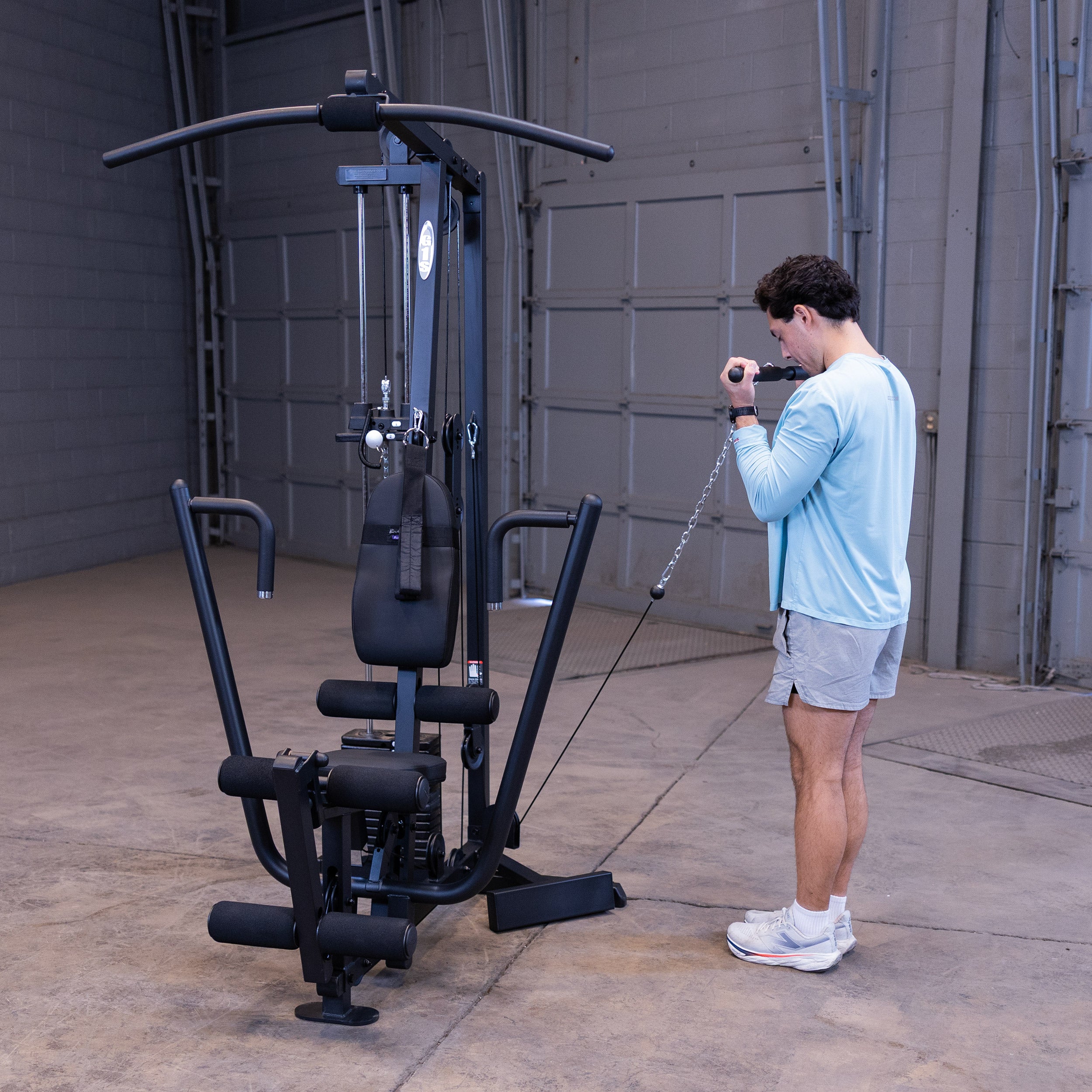 Person performing standing cable biceps curls on the Body-Solid G1B multi station home gym to strengthen the biceps