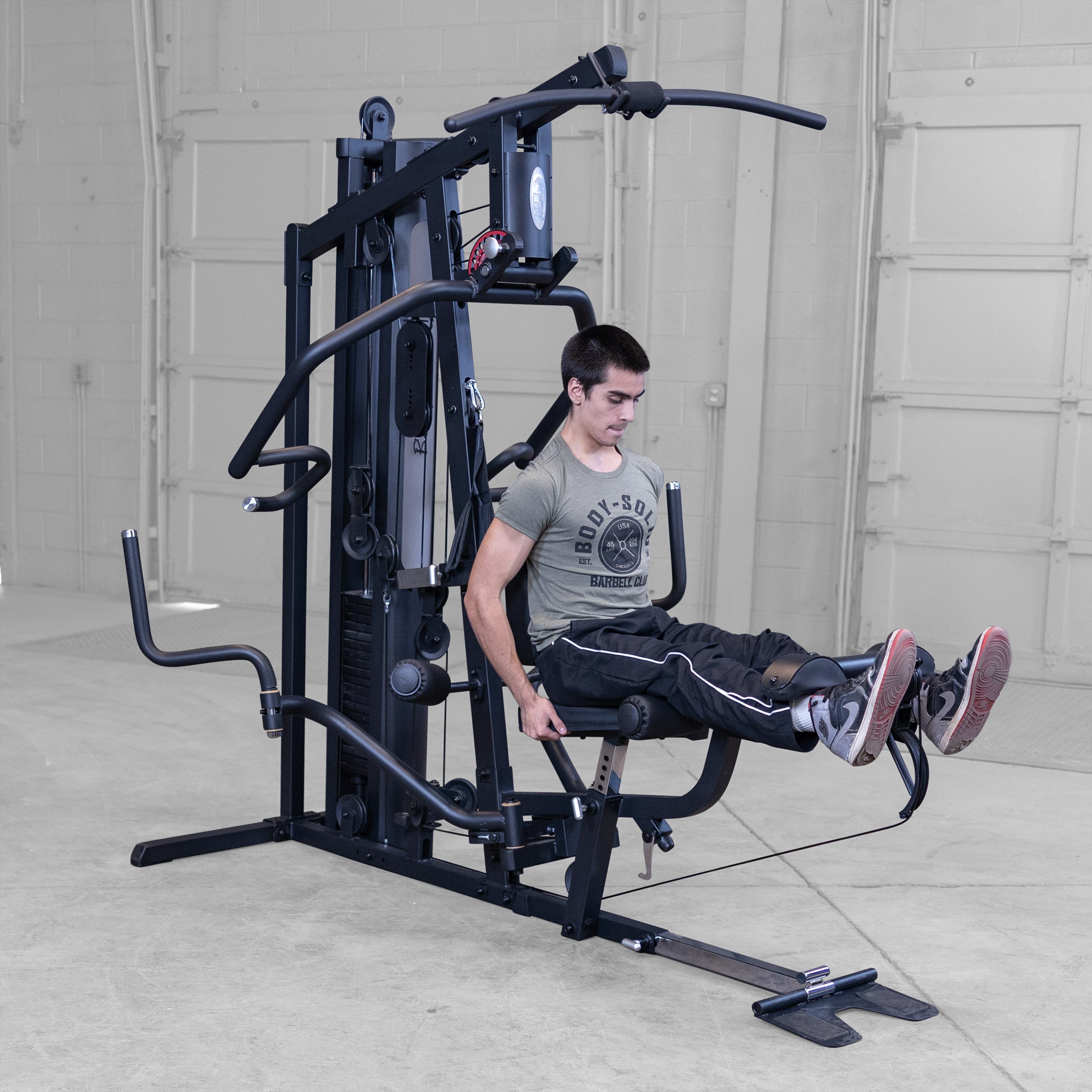 Person performing leg extensions on the Body-Solid G5B multi station home gym to strengthen the quadriceps and improve lower body strength