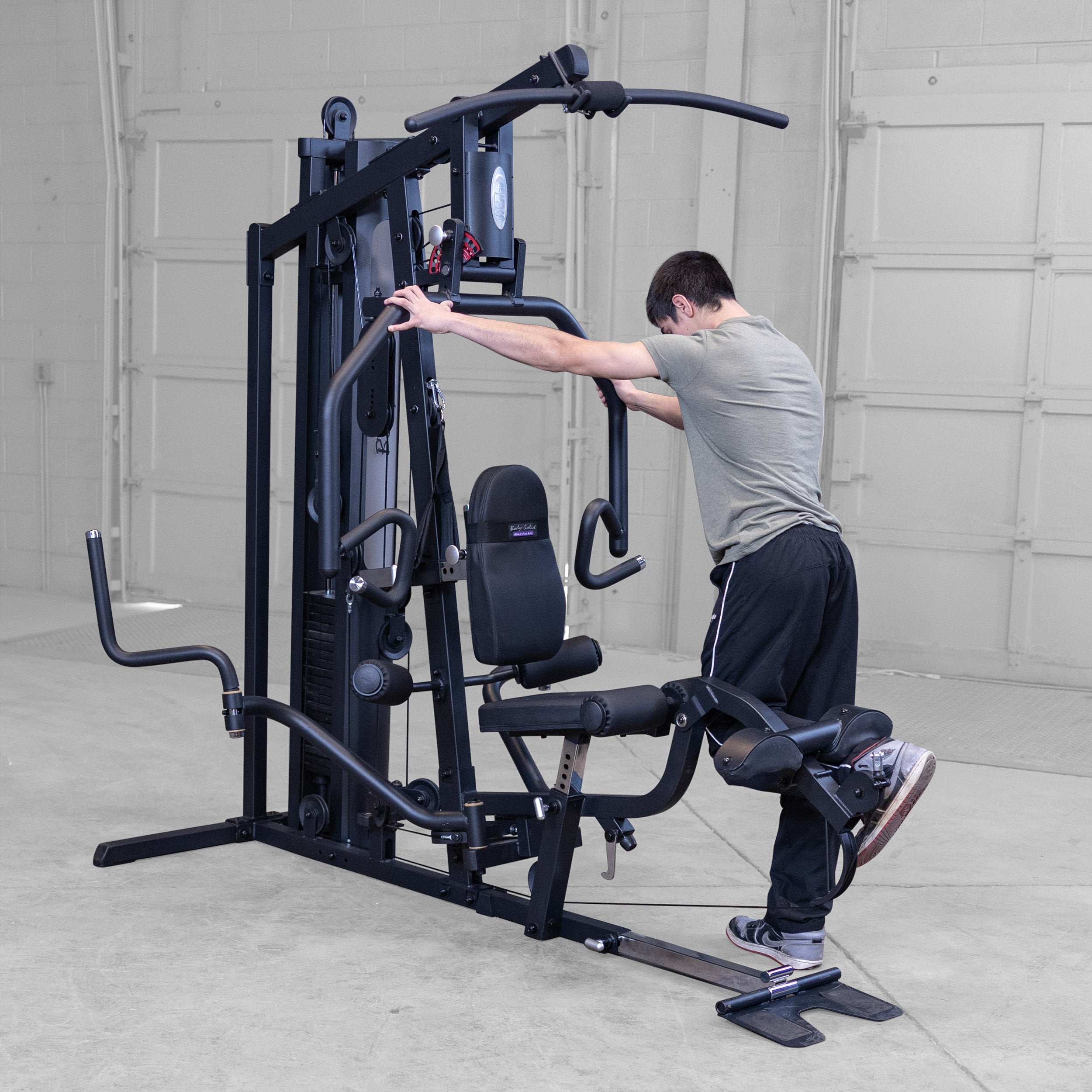 Person performing standing leg curls on the Body-Solid G5B multi station home gym to strengthen the hamstrings and glutes