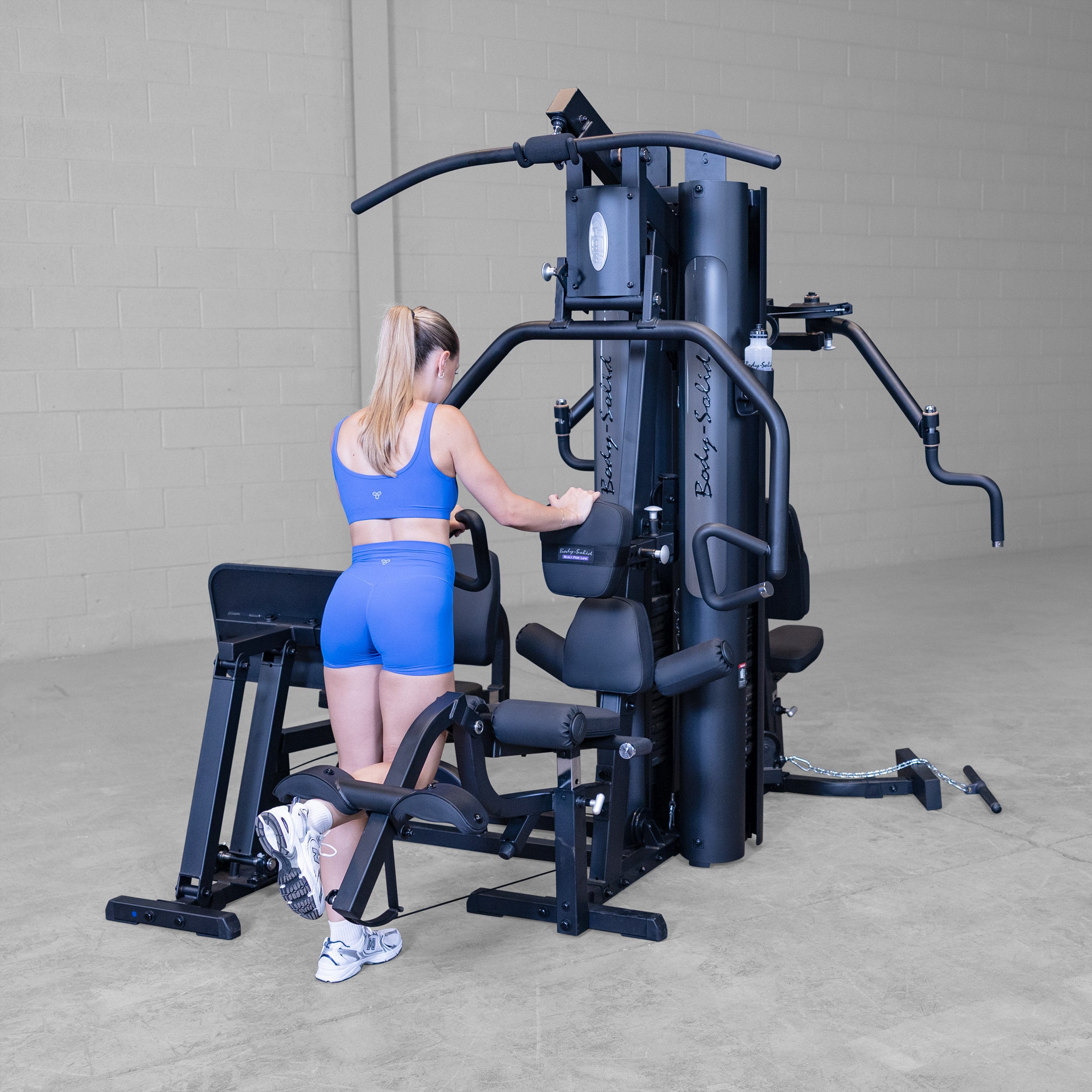 Person performing standing leg curl exercise on the Body-Solid G9B dual stack multi station home gym using the integrated leg curl station