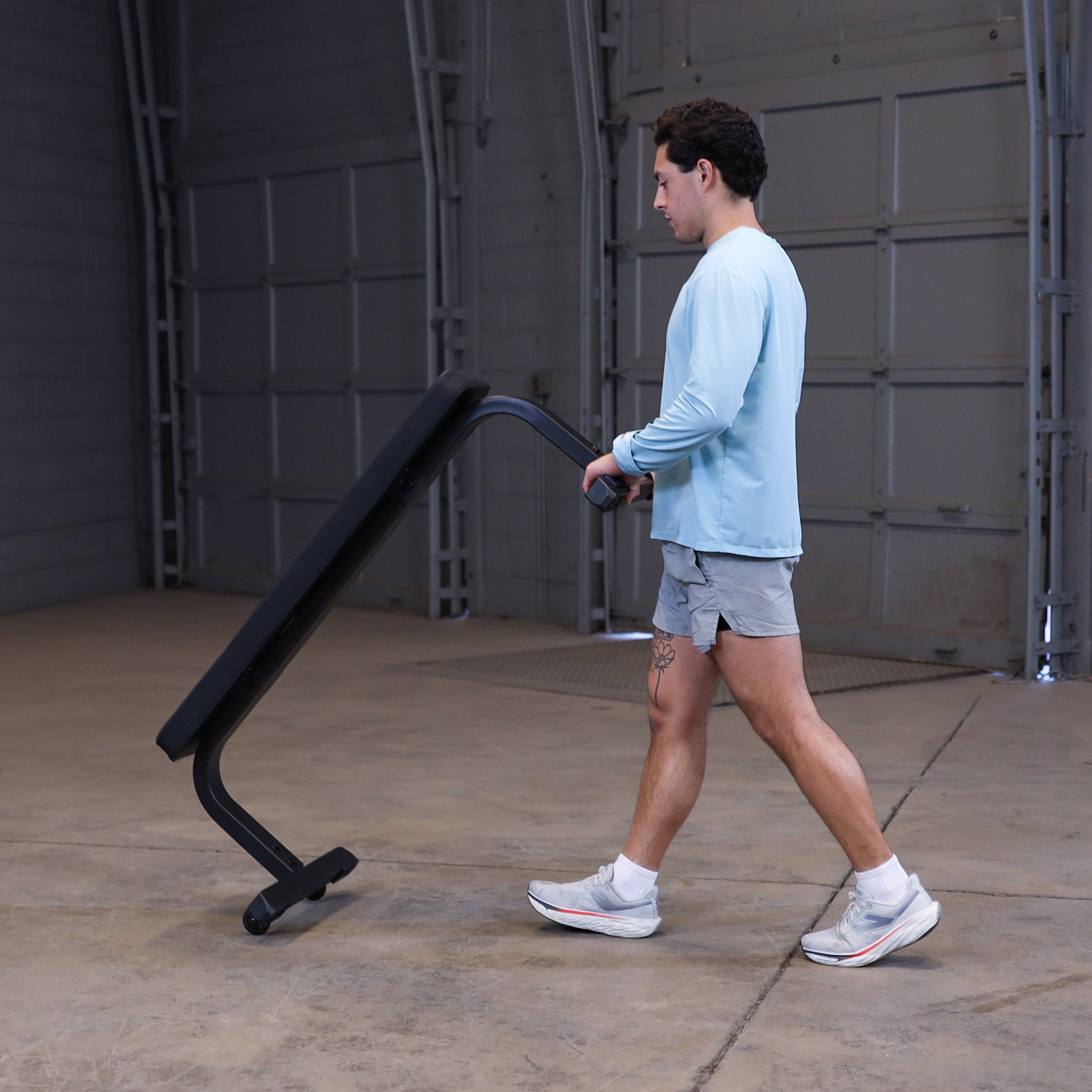 Person moving the Body-Solid GFB350B flat bench using the integrated transport wheels