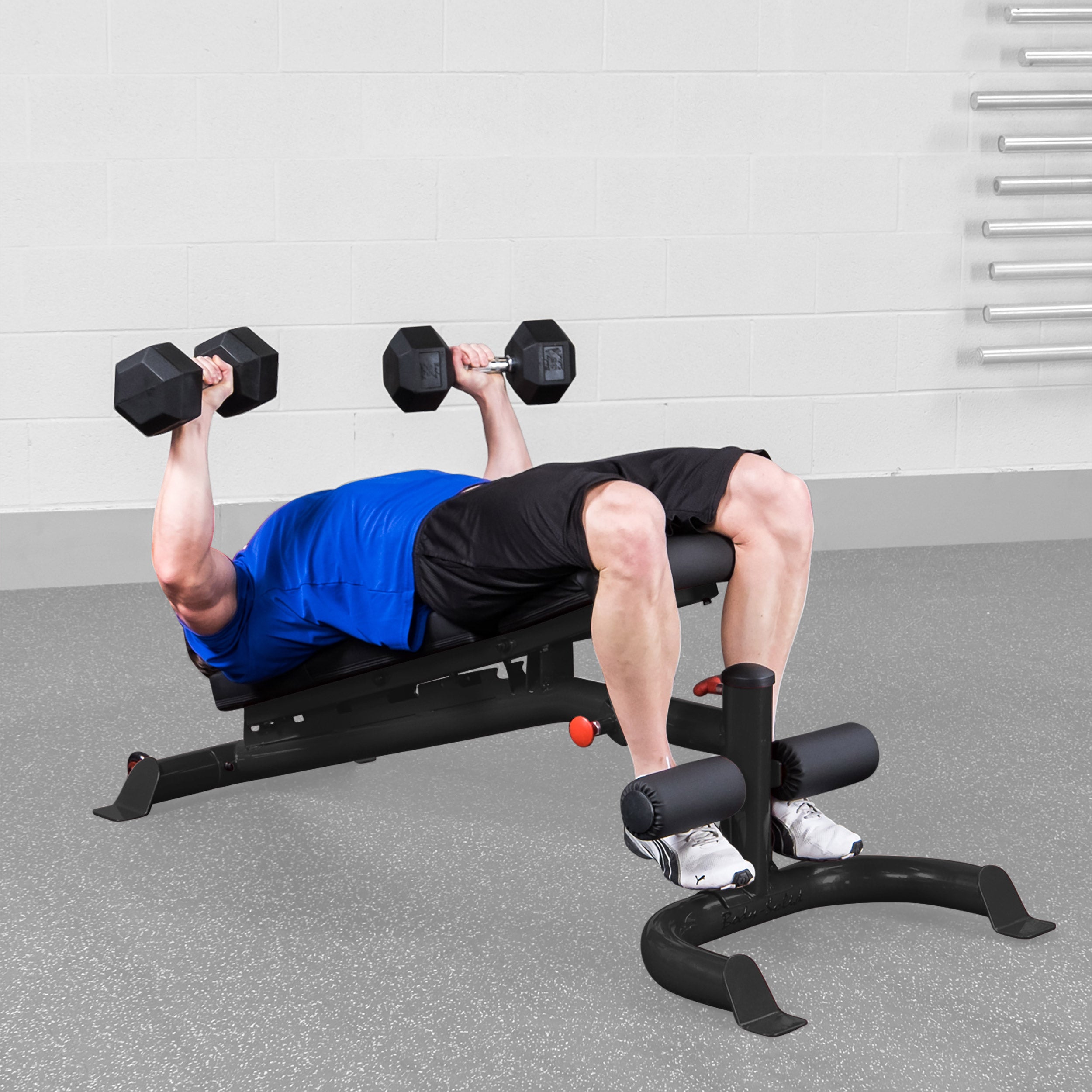 Person performing decline dumbbell press on Body Solid GFID100B adjustable weight bench in a home gym