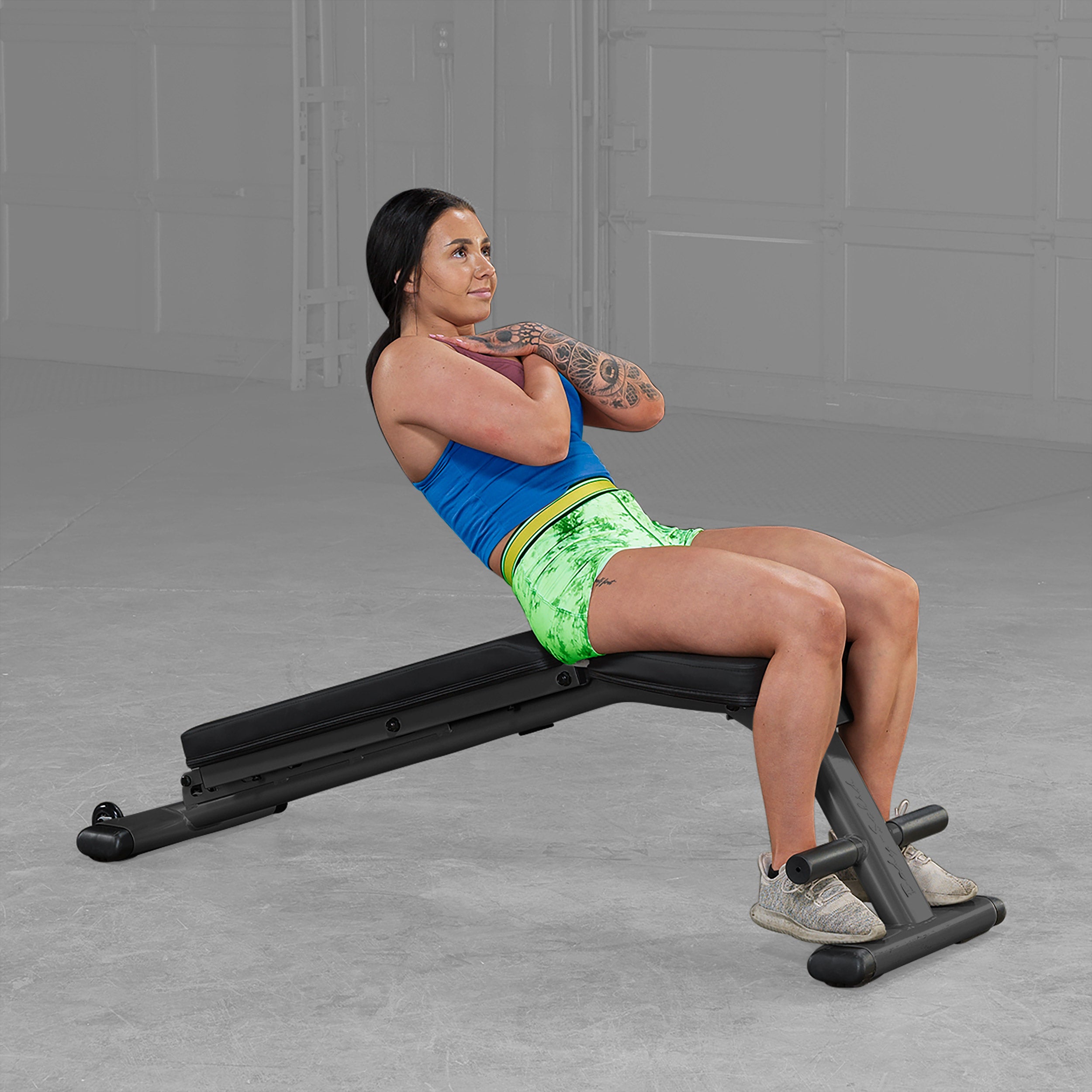 Person performing decline sit ups on Body Solid GFID225B folding adjustable weight bench in a home gym