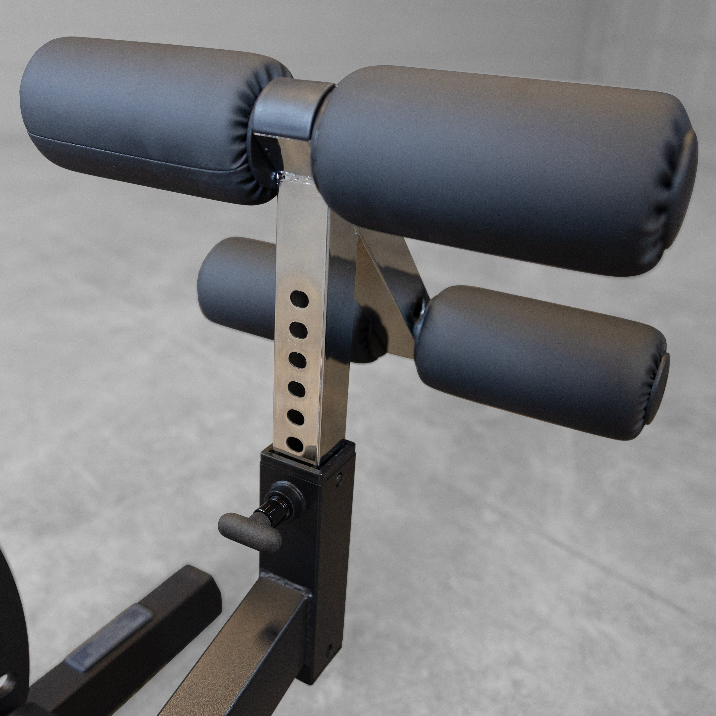 Body-Solid GFID71B Heavy Duty Flat Incline Decline Bench close-up of the adjustable leg hold-down attachment with height adjustment holes and oversized foam rollers for secure positioning during decline exercises