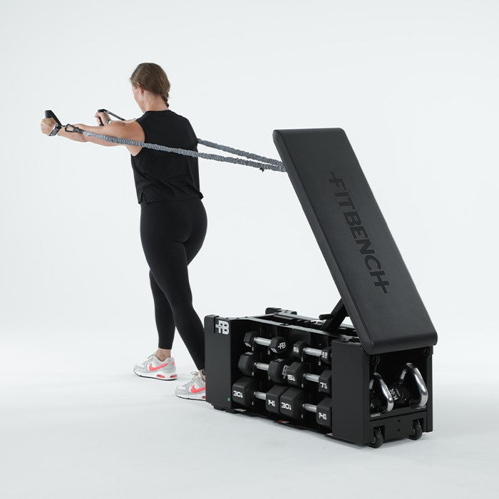 Woman performing resistance band chest fly exercise with FITBENCH One NXT Gen workout bench