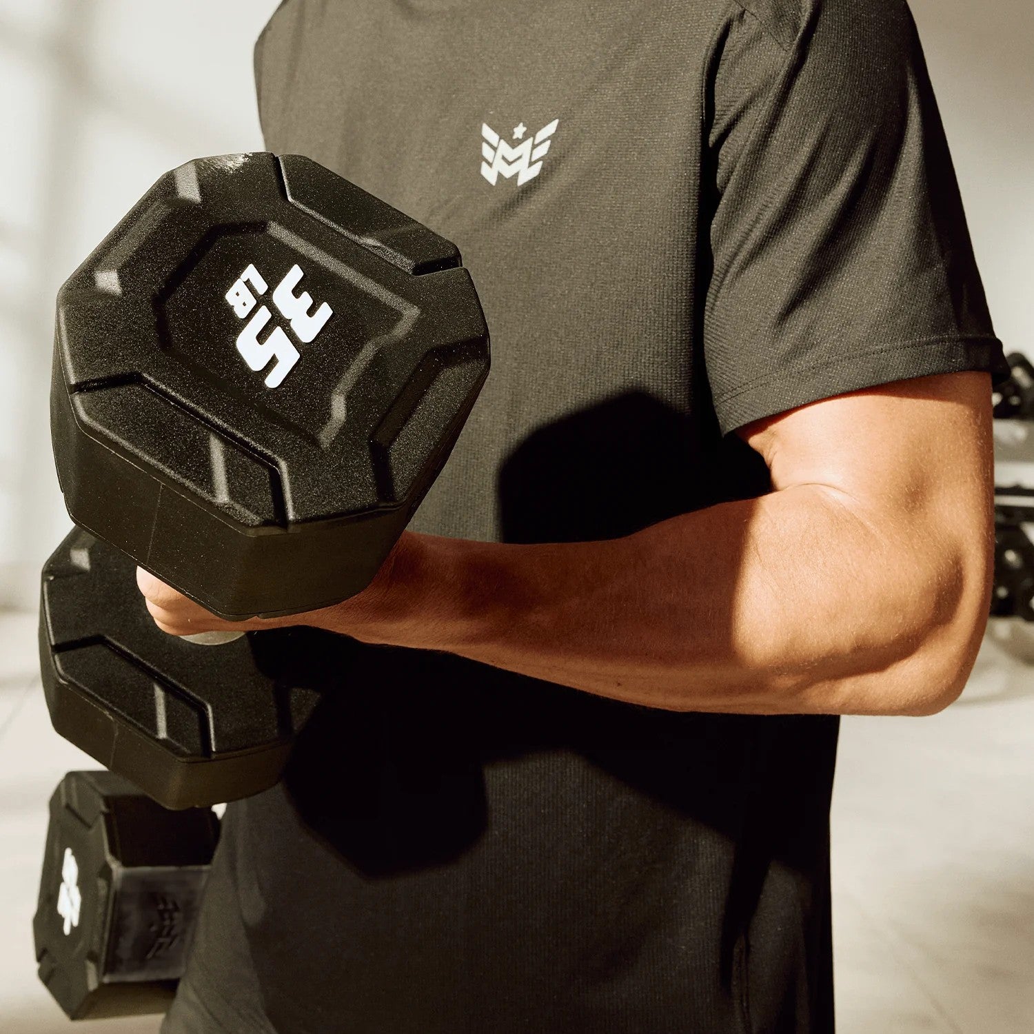 Athlete performing dumbbell curls using Major Fitness urethane octagonal shield dumbbells with durable urethane coating and clear weight markings
