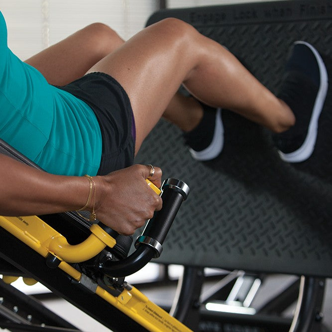 Close-up of a user performing a lower body exercise on the Total Gym ELEVATE Jump showing the ergonomic handles and foot platform