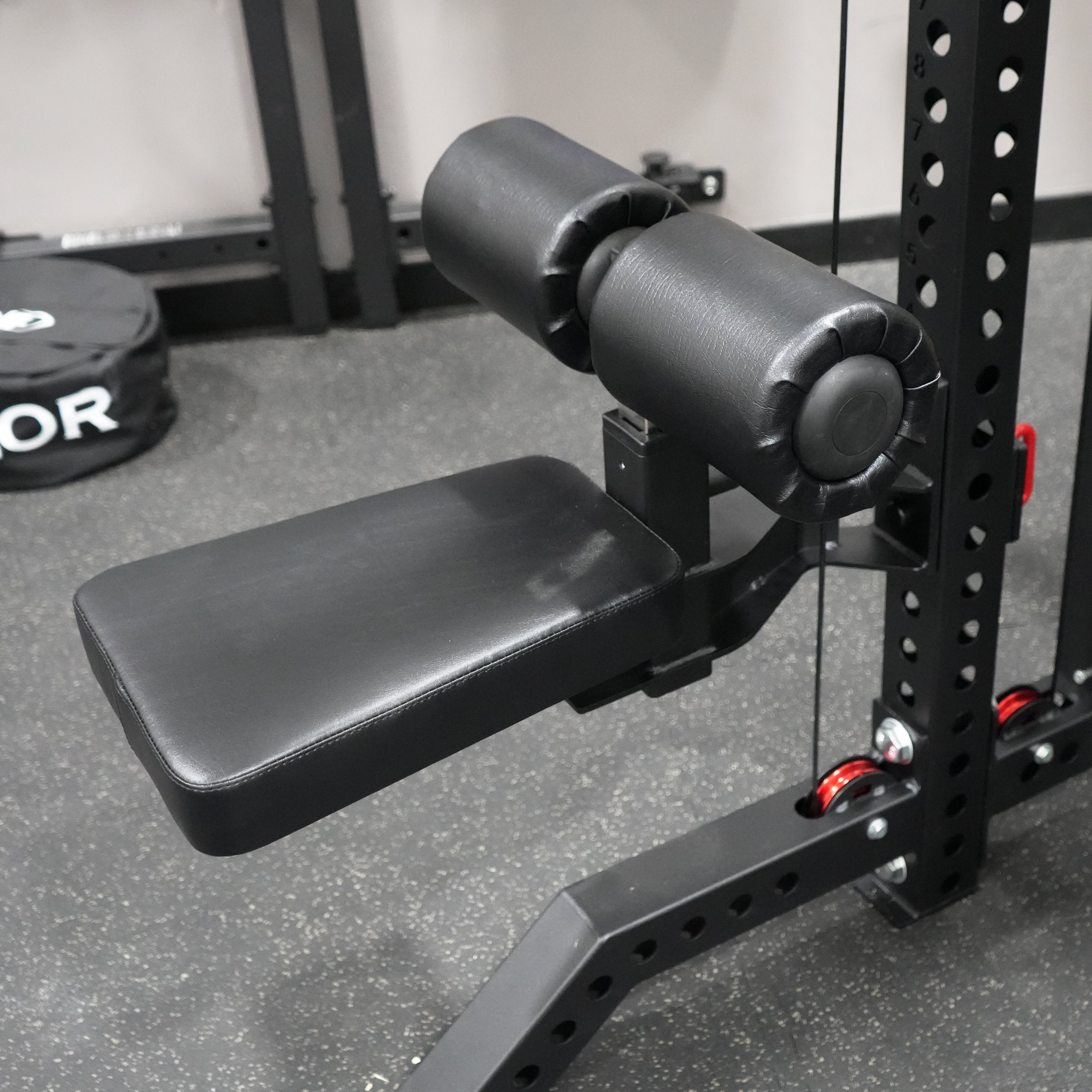 Close up view of the Valor Fitness BD-83 lat pulldown seat attachment with adjustable leg rollers and padded seat mounted to the power rack frame