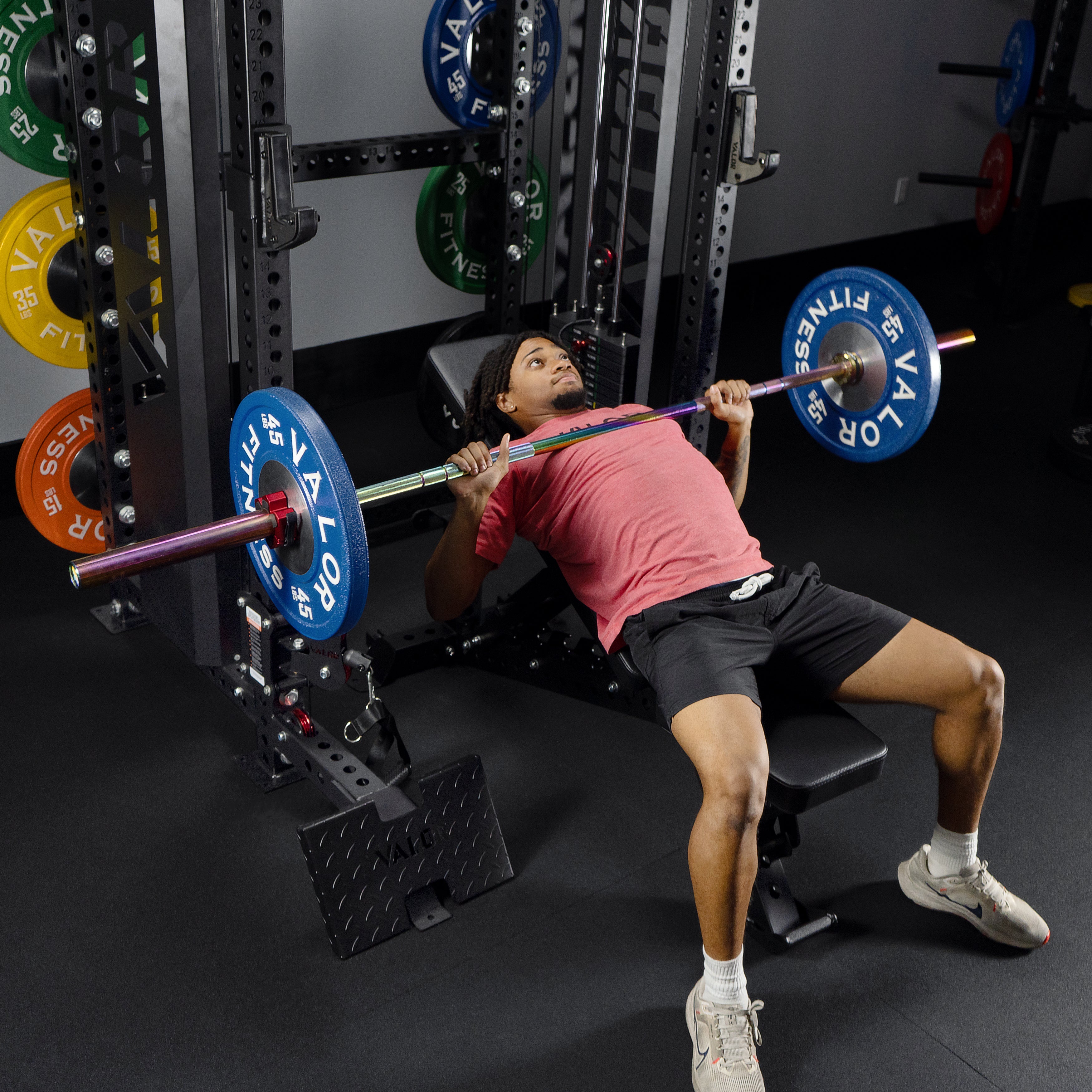 Athlete performing incline barbell bench press on the Valor Fitness BD-83 functional trainer power rack with safety spotter arms and adjustable bench