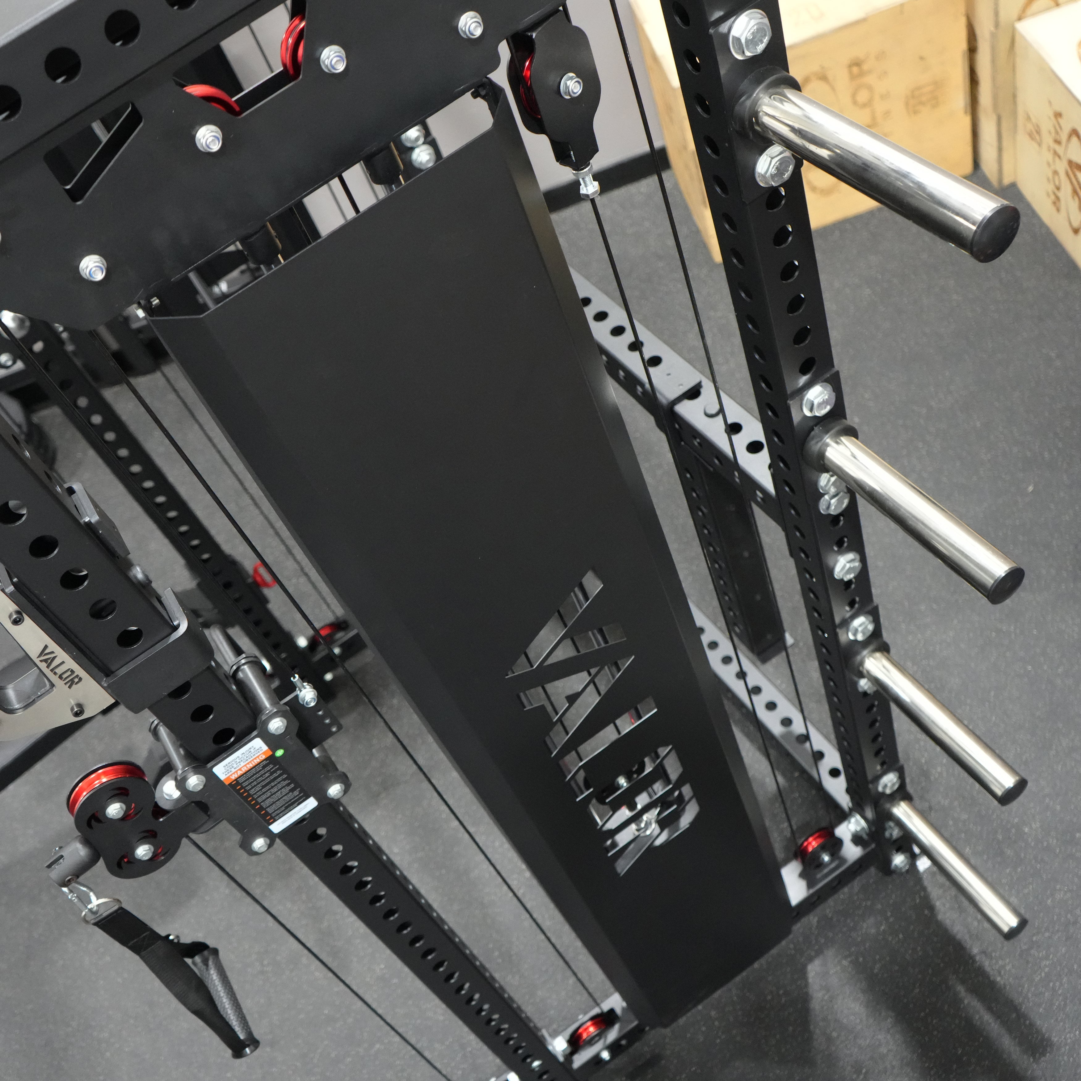Rear angle view of the Valor Fitness BD-83 functional trainer power rack with integrated Olympic plate storage pegs and protective weight stack shroud
