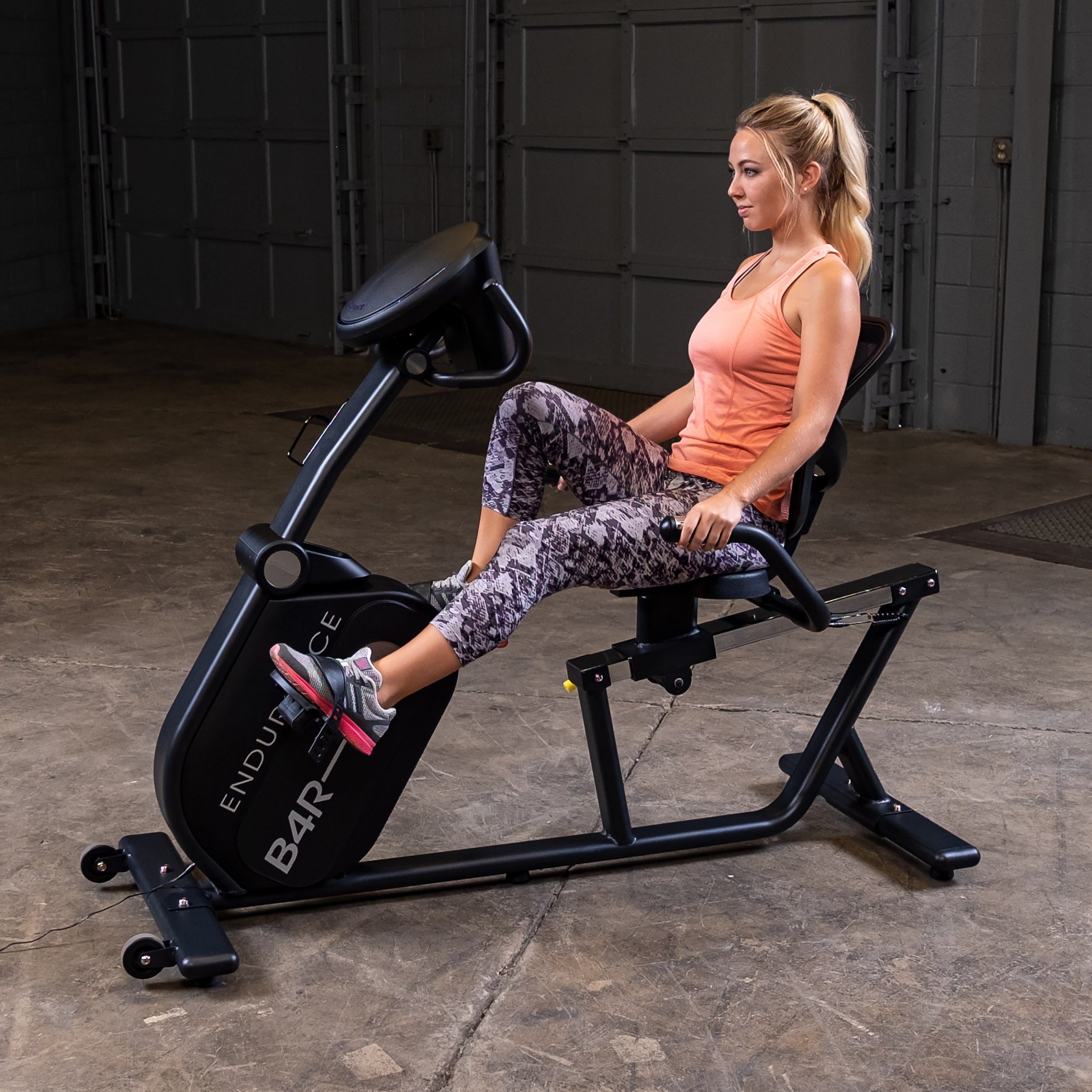 Side view of woman using Body-Solid Endurance B4RB recumbent bike