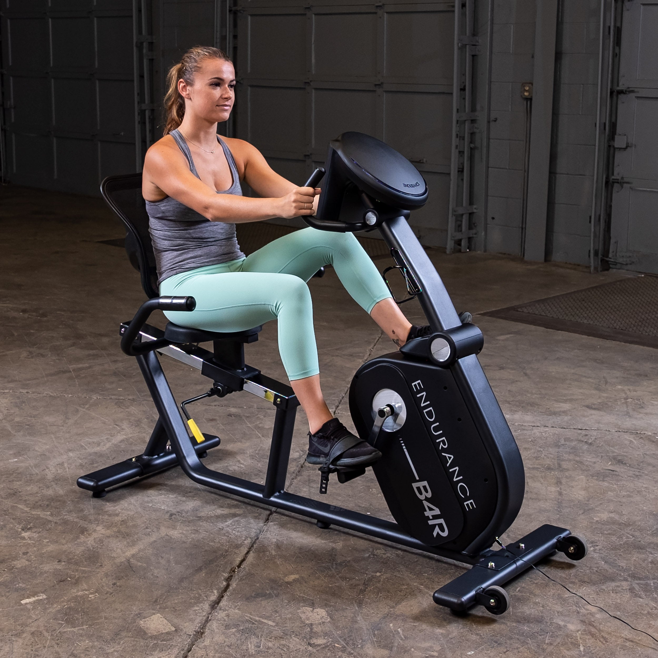 Woman using Body-Solid Endurance B4RB recumbent bike for cardio workout