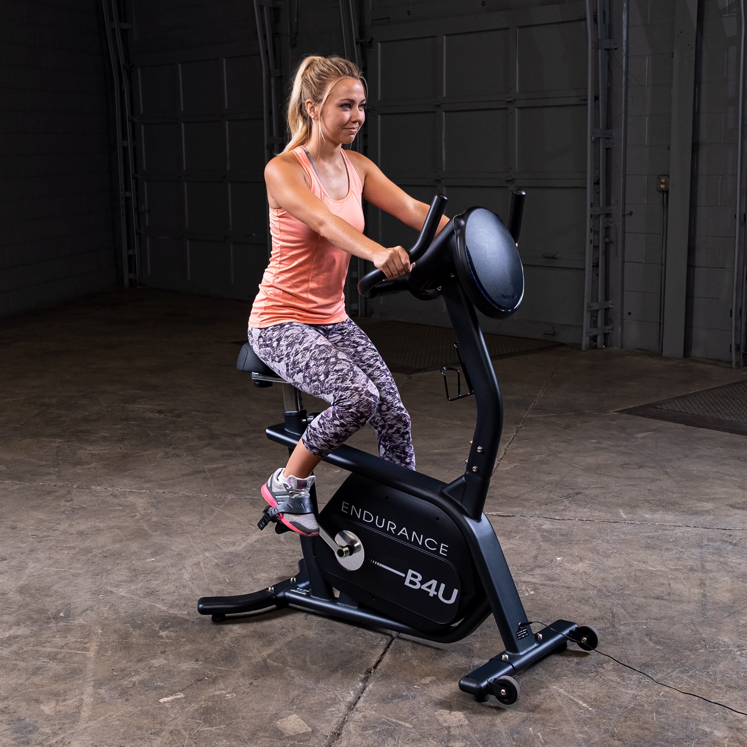 Woman riding Body-Solid Endurance B4UB upright exercise bike during cardio workout