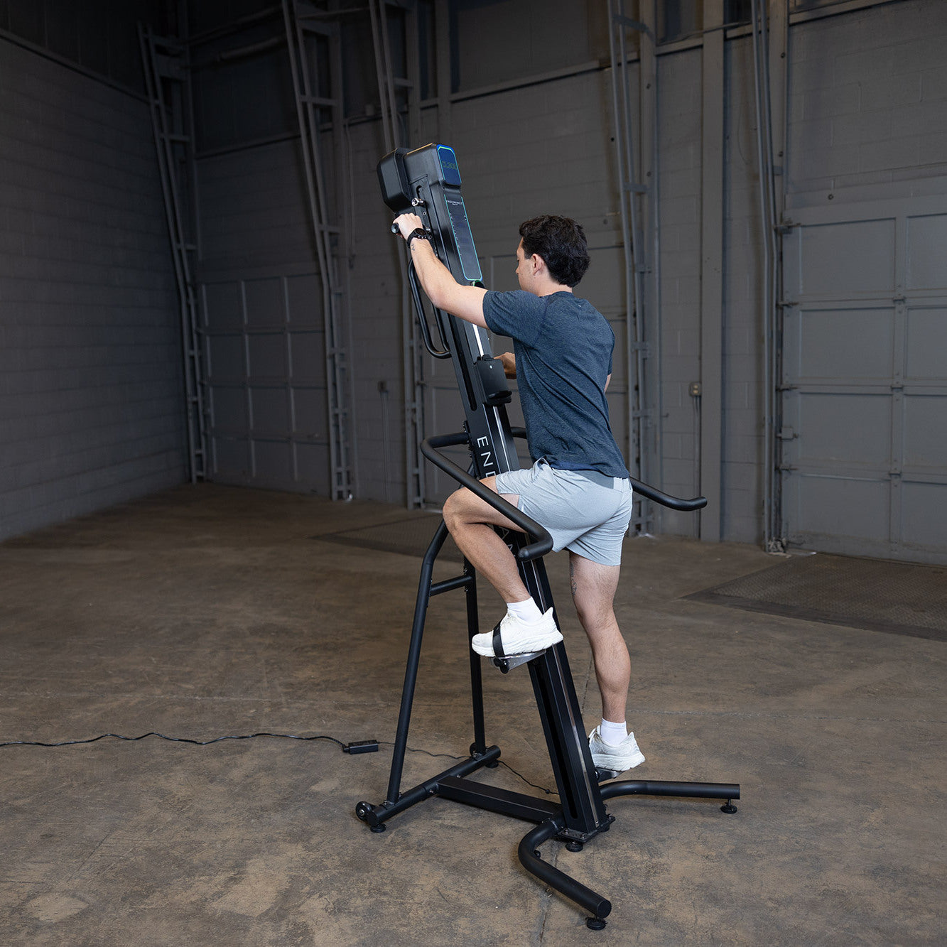 Man using Body-Solid Endurance CL300 vertical climber for full-body low-impact cardio workout in home gym setting