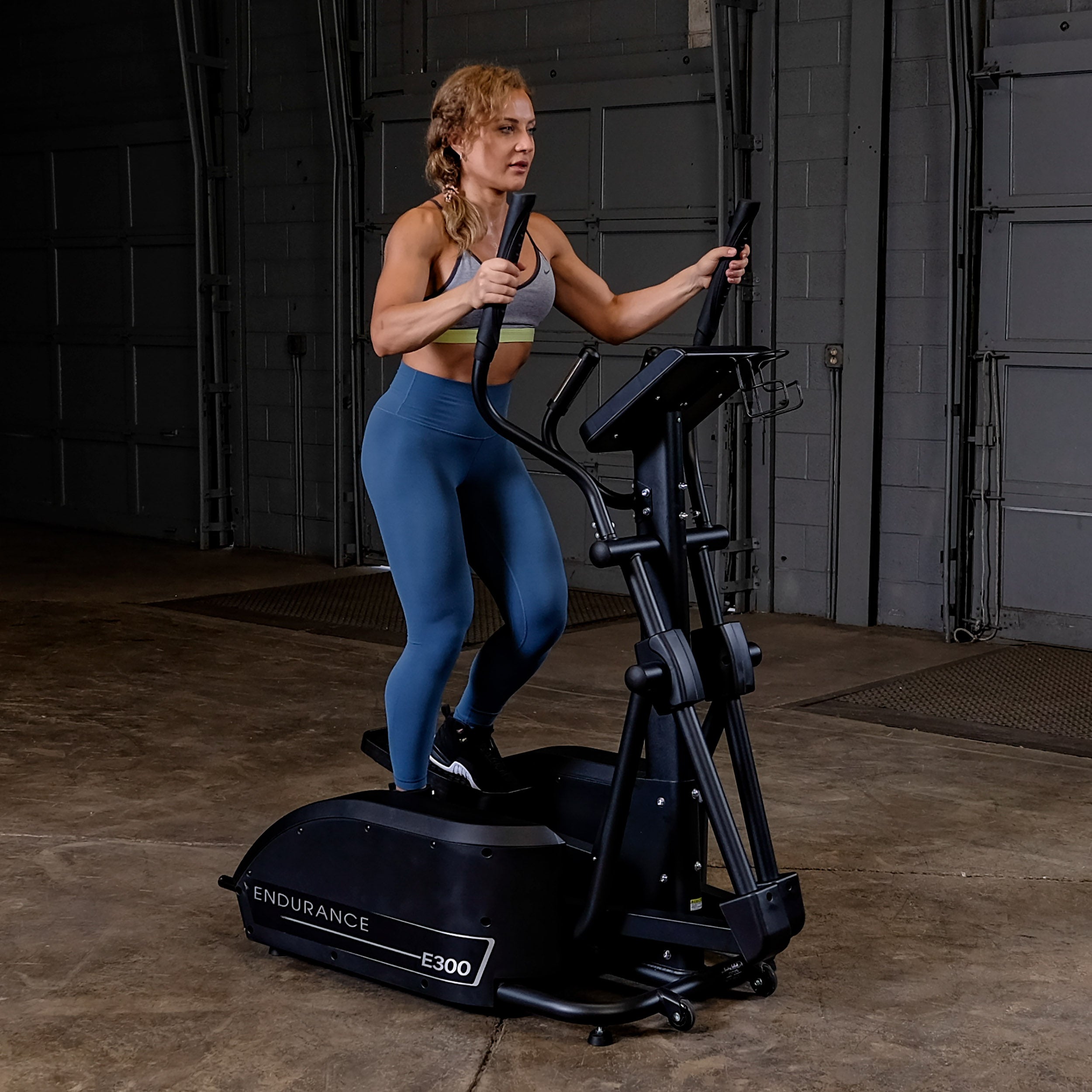 Woman using Body-Solid Endurance E300 elliptical trainer for low-impact full-body cardio workout