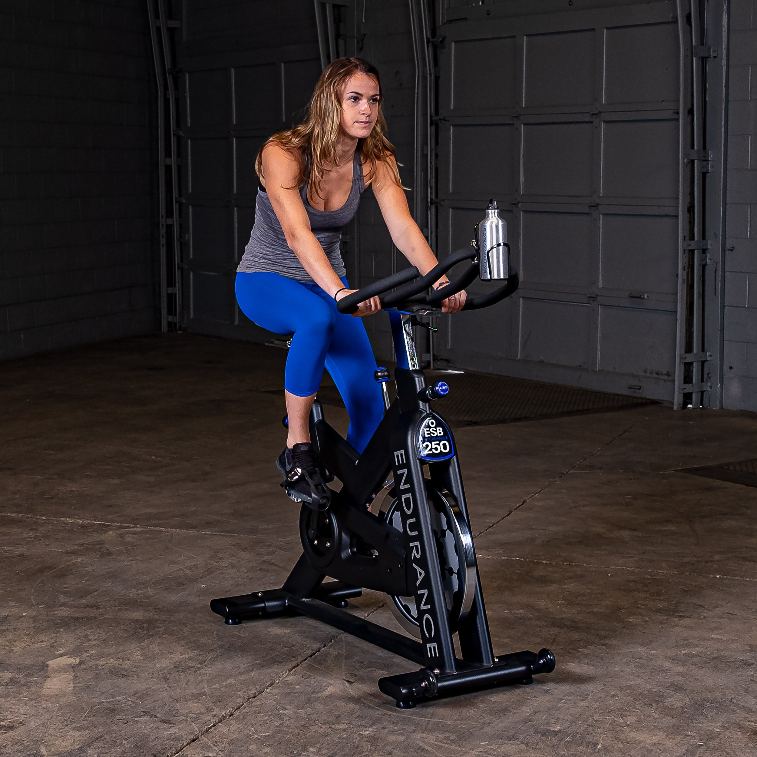 Person riding the Body-Solid Endurance ESB250 indoor training cycle in a seated position during an indoor cardio workout