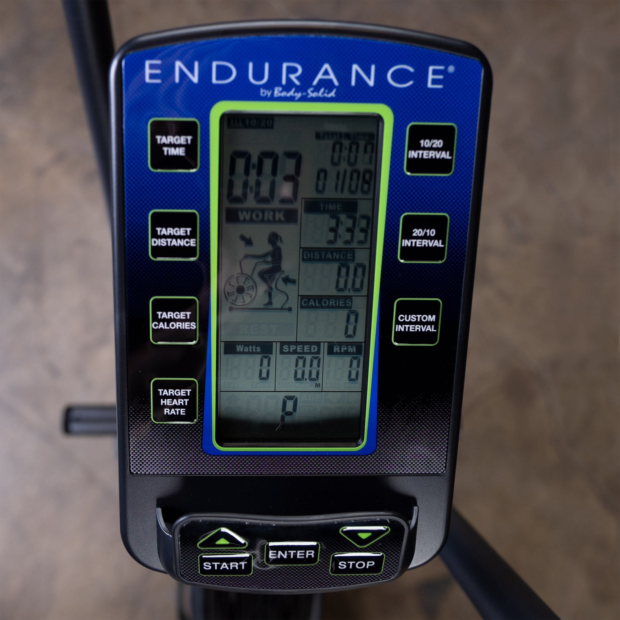 Close-up of the Body-Solid Endurance FB300B fan bike LCD console displaying workout metrics, interval training programs, target goals, watts, speed, RPM, time, distance, calories, and heart rate tracking