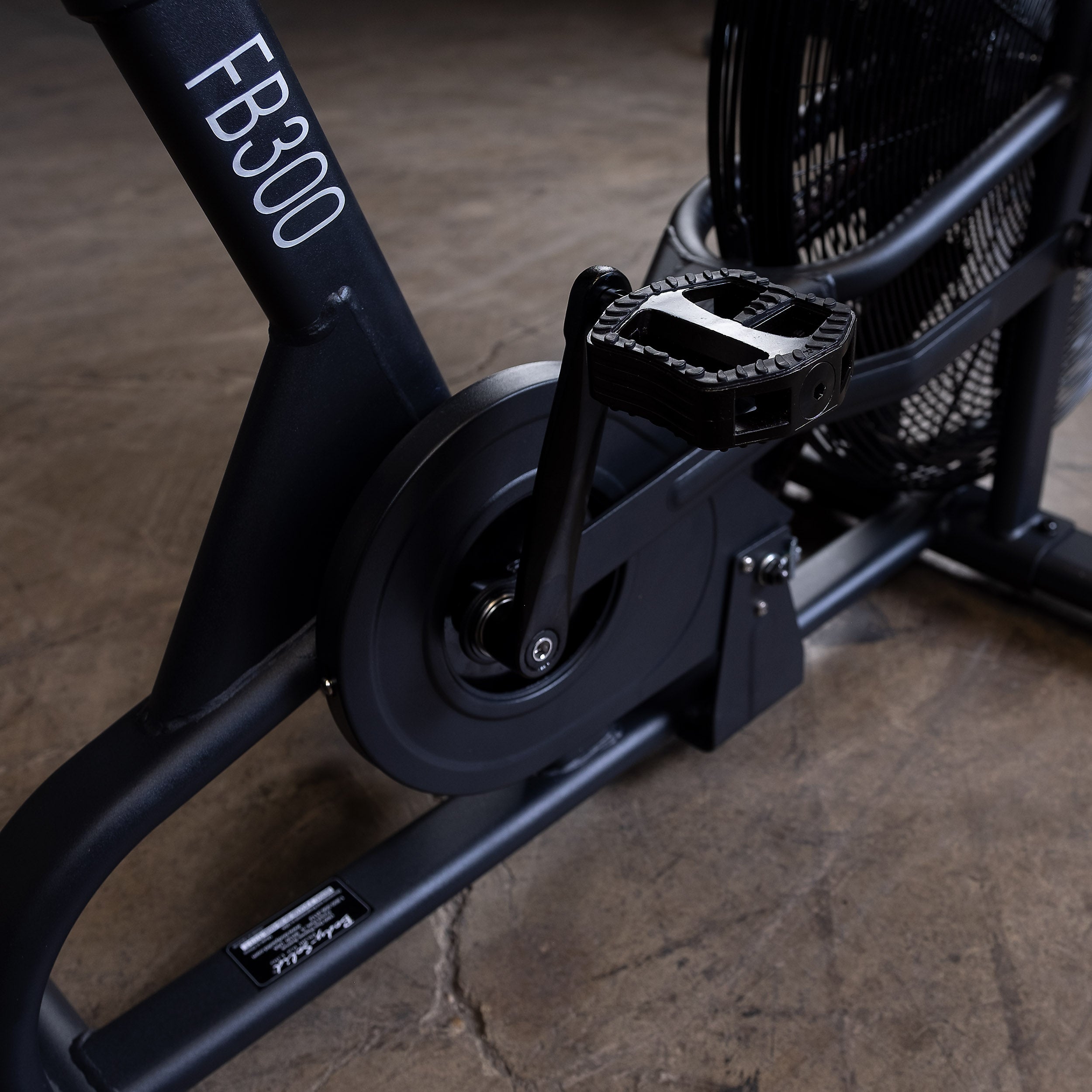 Close-up of the Body-Solid Endurance FB300B fan bike drive system, crank arm, and oversized pedal showing the durable commercial-grade construction