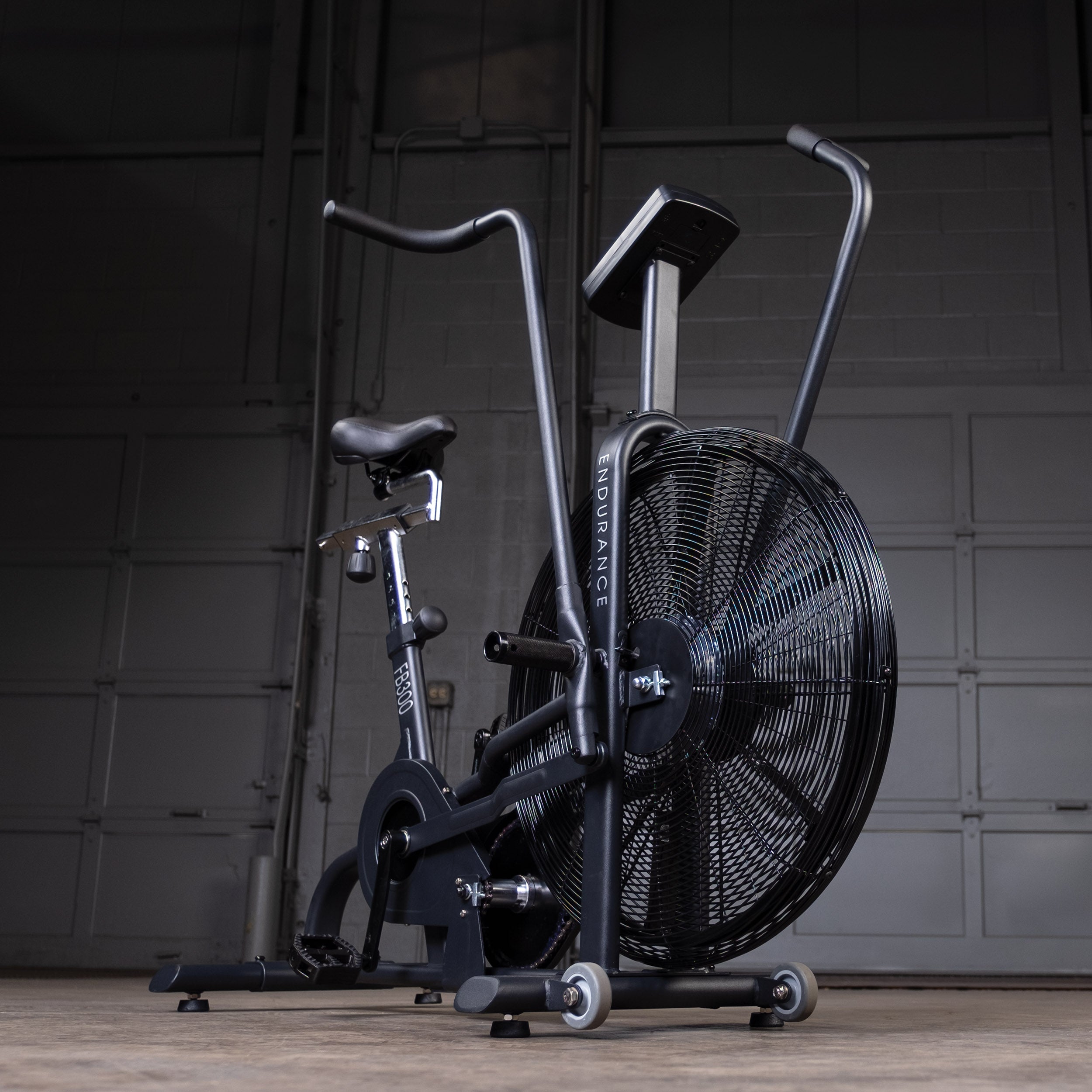 Low front angle view of the Body-Solid Endurance FB300B fan bike highlighting the large air resistance fan, moving handlebars, adjustable seat, console, and transport wheels