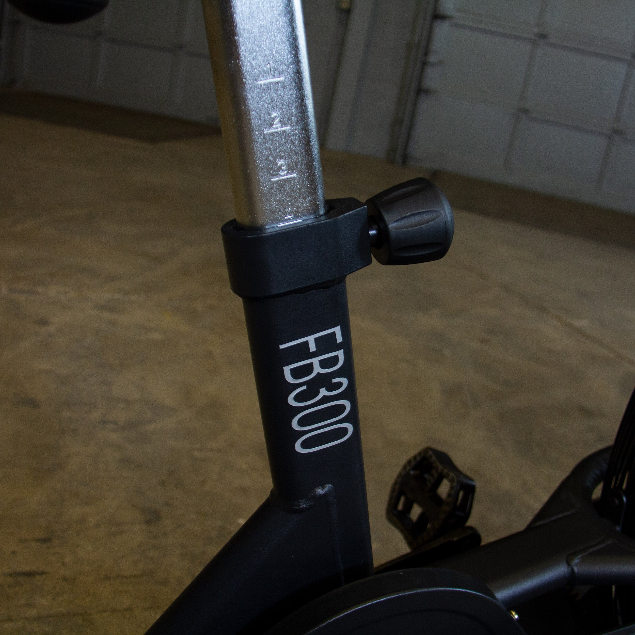 Close-up of the Body-Solid Endurance FB300B fan bike seat height adjustment post with numbered height markings and adjustment knob