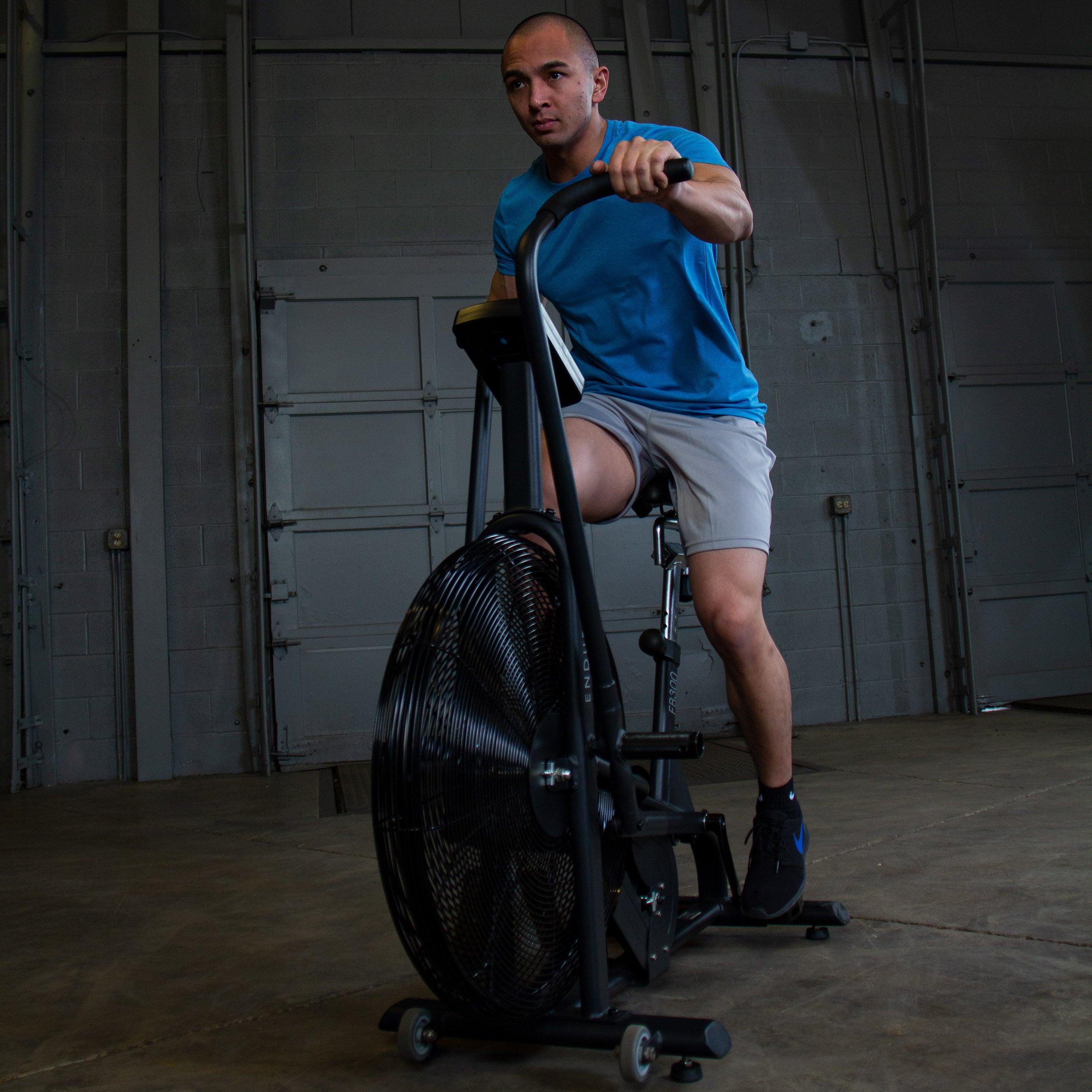 Body-Solid Endurance FB300B fan bike in use during a high-intensity cardio workout shown from the front with moving handlebars and air resistance fan