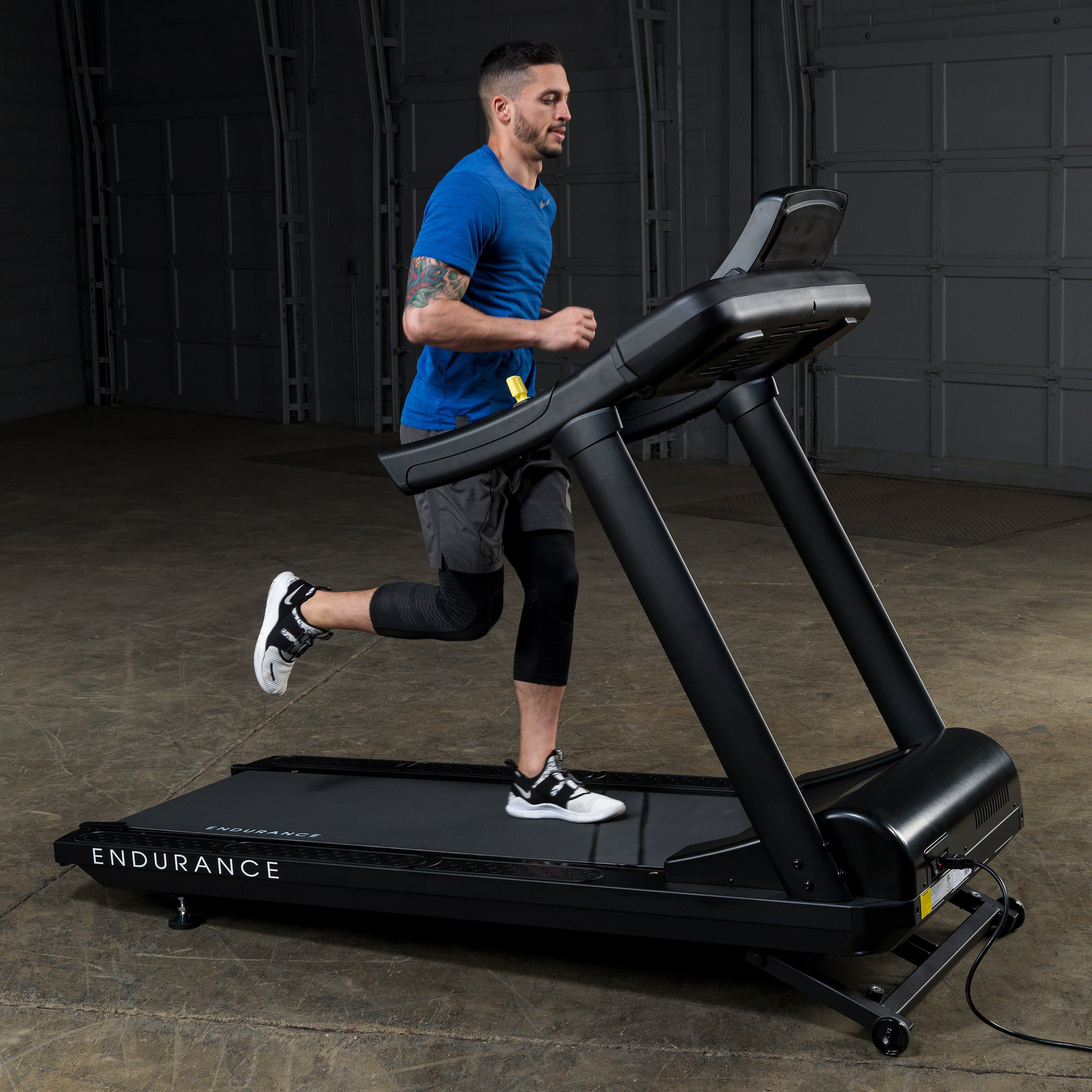 Man running on Body-Solid Endurance T150 commercial treadmill in gym setting