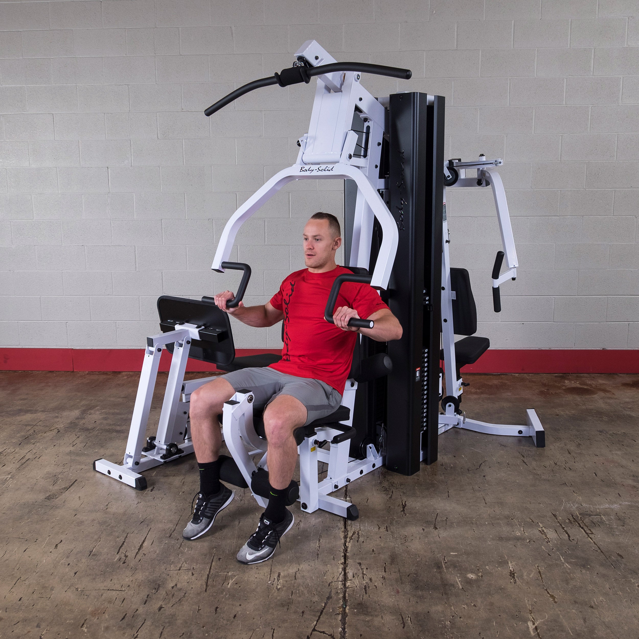 Person performing chest press exercises on the Body-Solid EXM3000LPS dual stack multi-station gym
