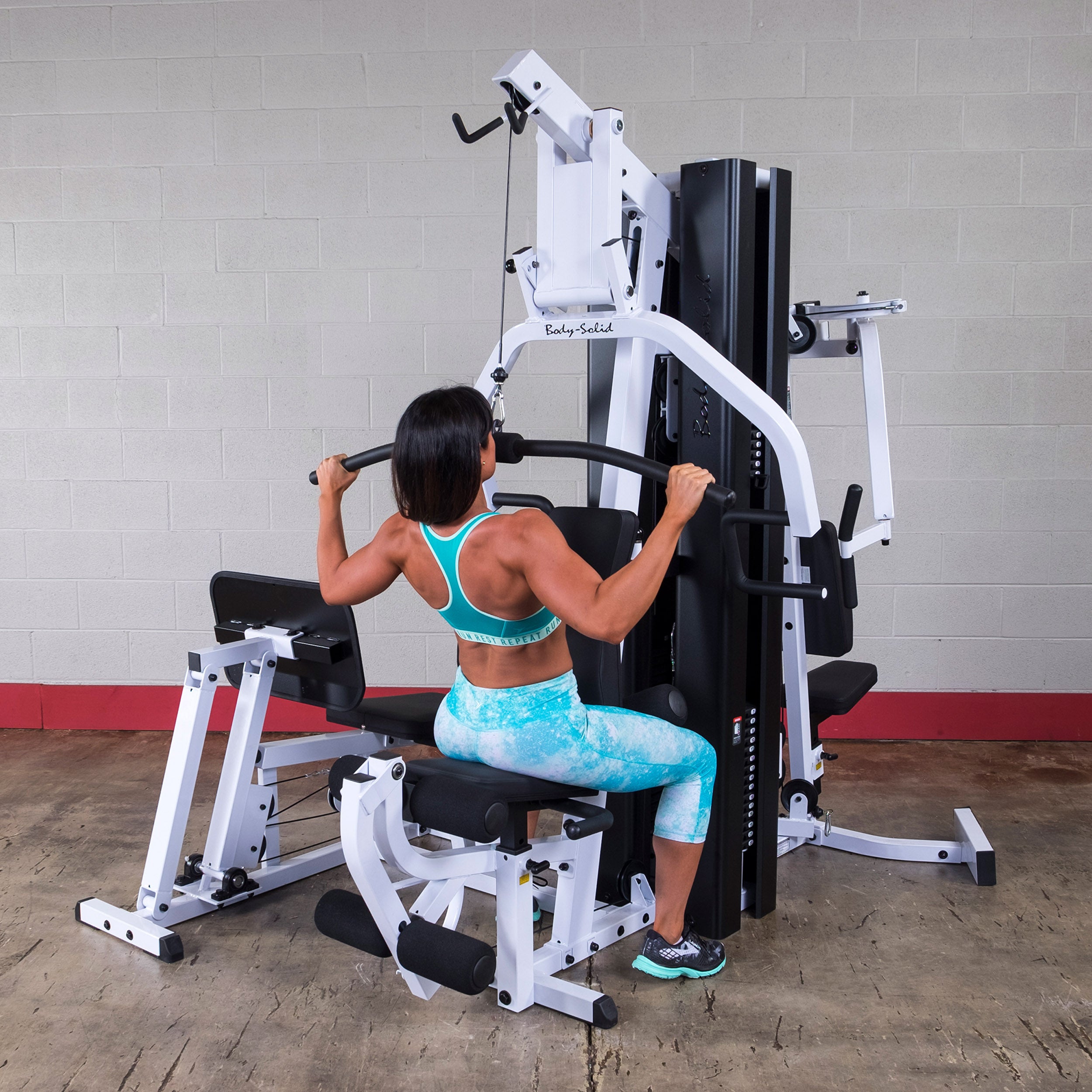 Person performing lat pulldown exercises on the Body-Solid EXM3000LPS dual stack multi-station gym
