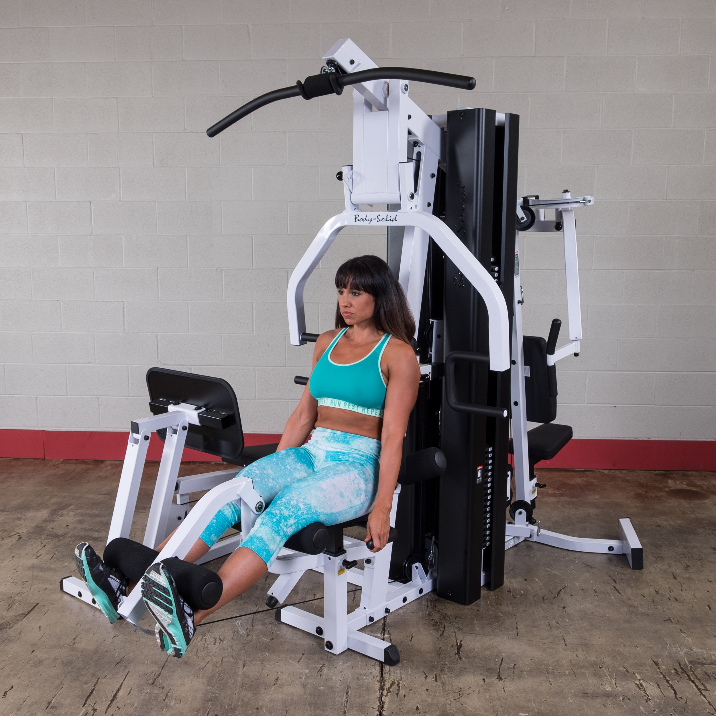 Person performing leg extension exercises on the Body-Solid EXM3000LPS dual stack multi-station gym