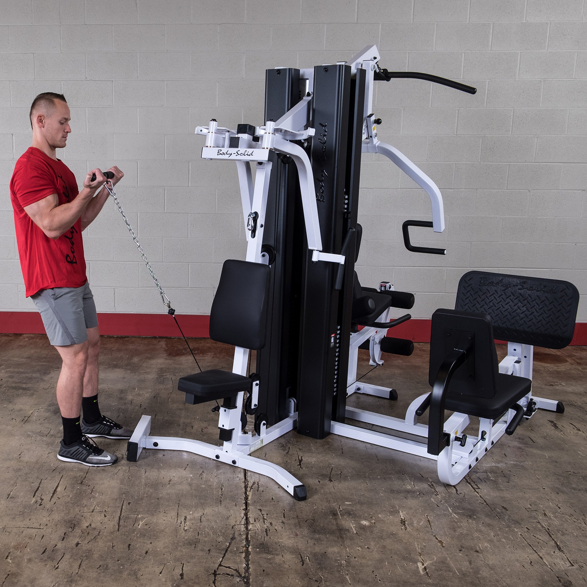 Person performing standing bicep curl exercises on the Body-Solid EXM3000LPS dual stack multi-station gym