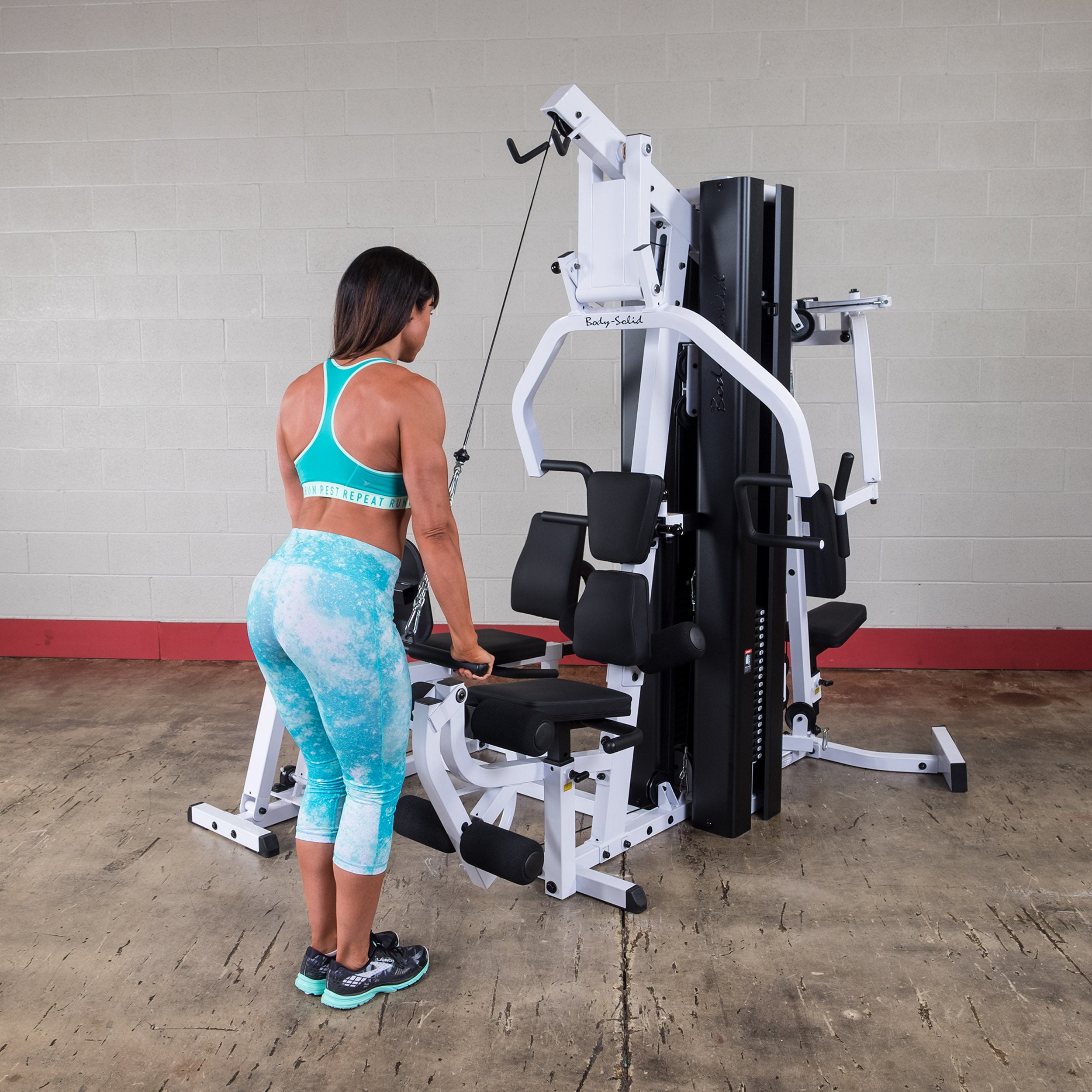 Person performing tricep pushdown exercises on the Body-Solid EXM3000LPS dual stack multi-station gym