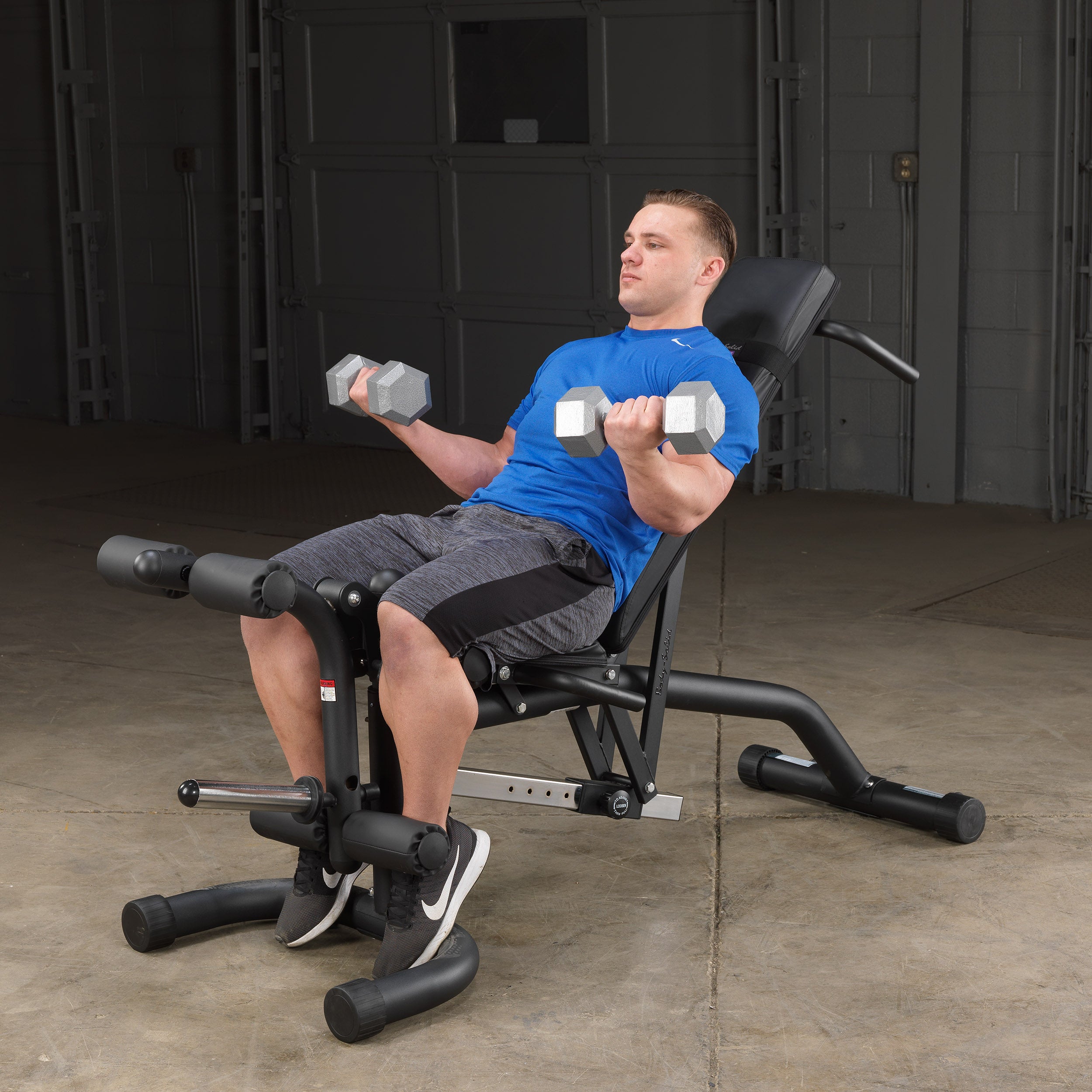 Person performing seated dumbbell curls on the Body-Solid FID46 leverage flat incline decline bench in the incline position