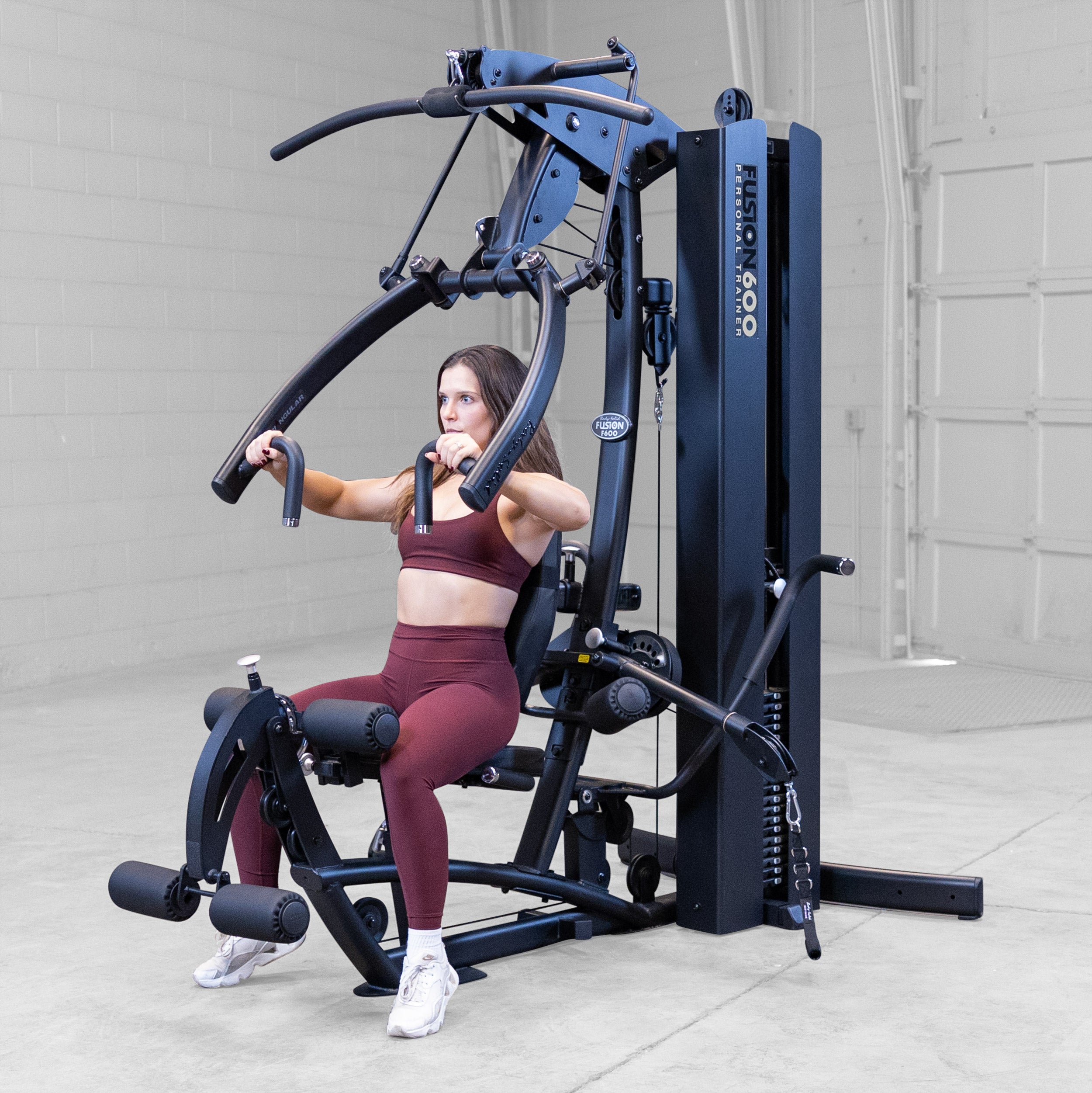 Woman performing a seated chest press on the Body-Solid Fusion 600B Personal Trainer