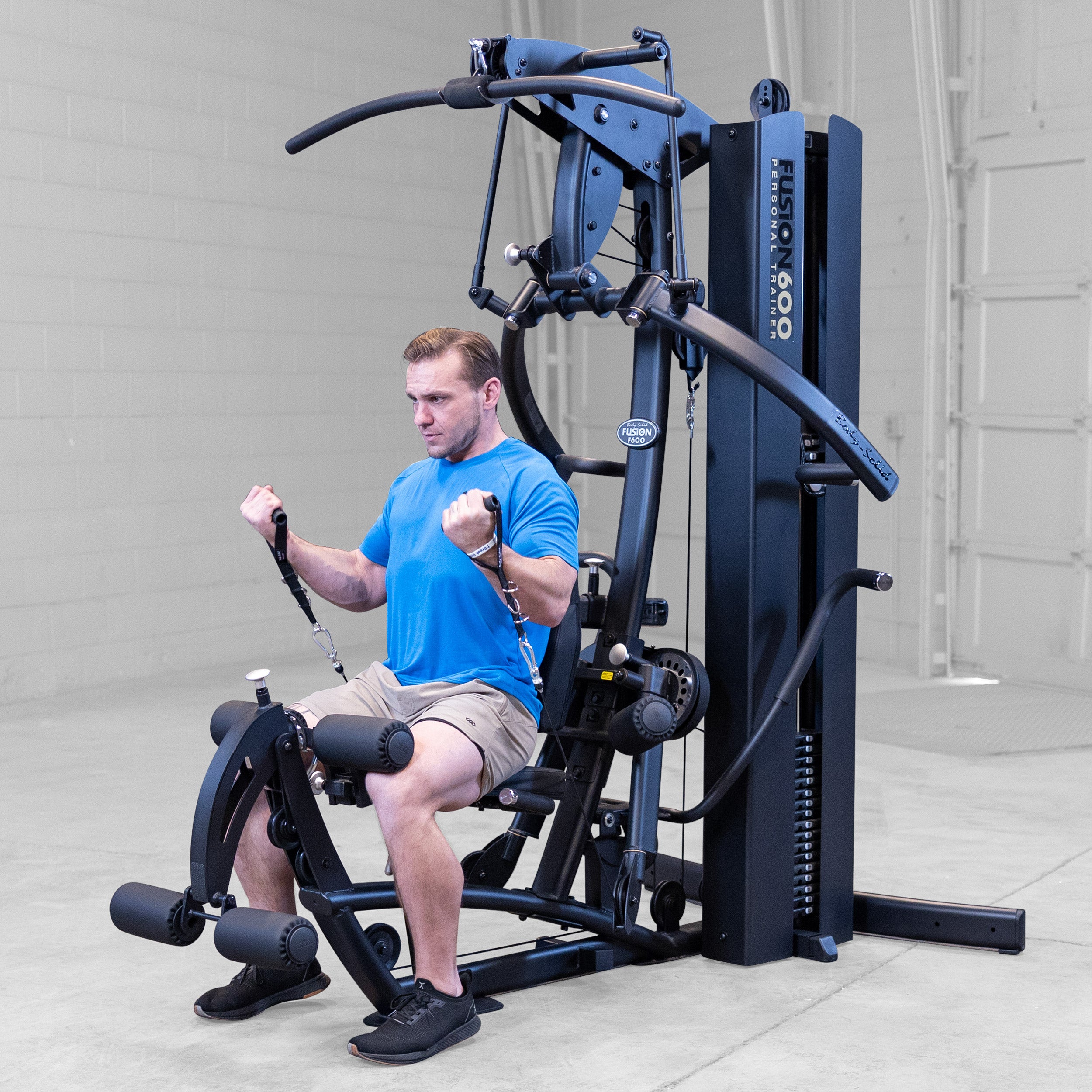 Man performing a seated biceps curl on the Body-Solid Fusion 600B Personal Trainer using the functional training handles