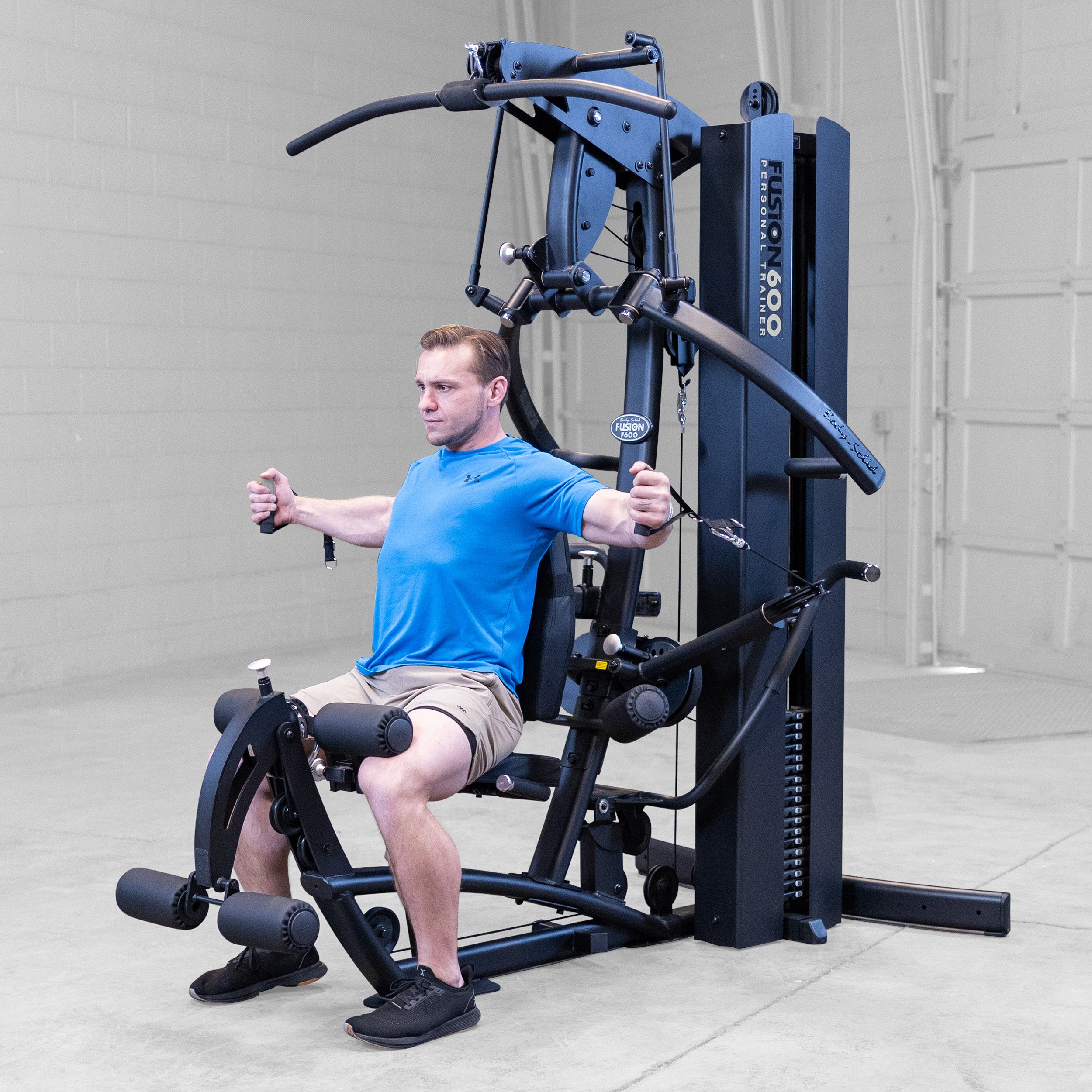 Man performing a seated cable chest fly on the Body-Solid Fusion 600B Personal Trainer using the functional training handles