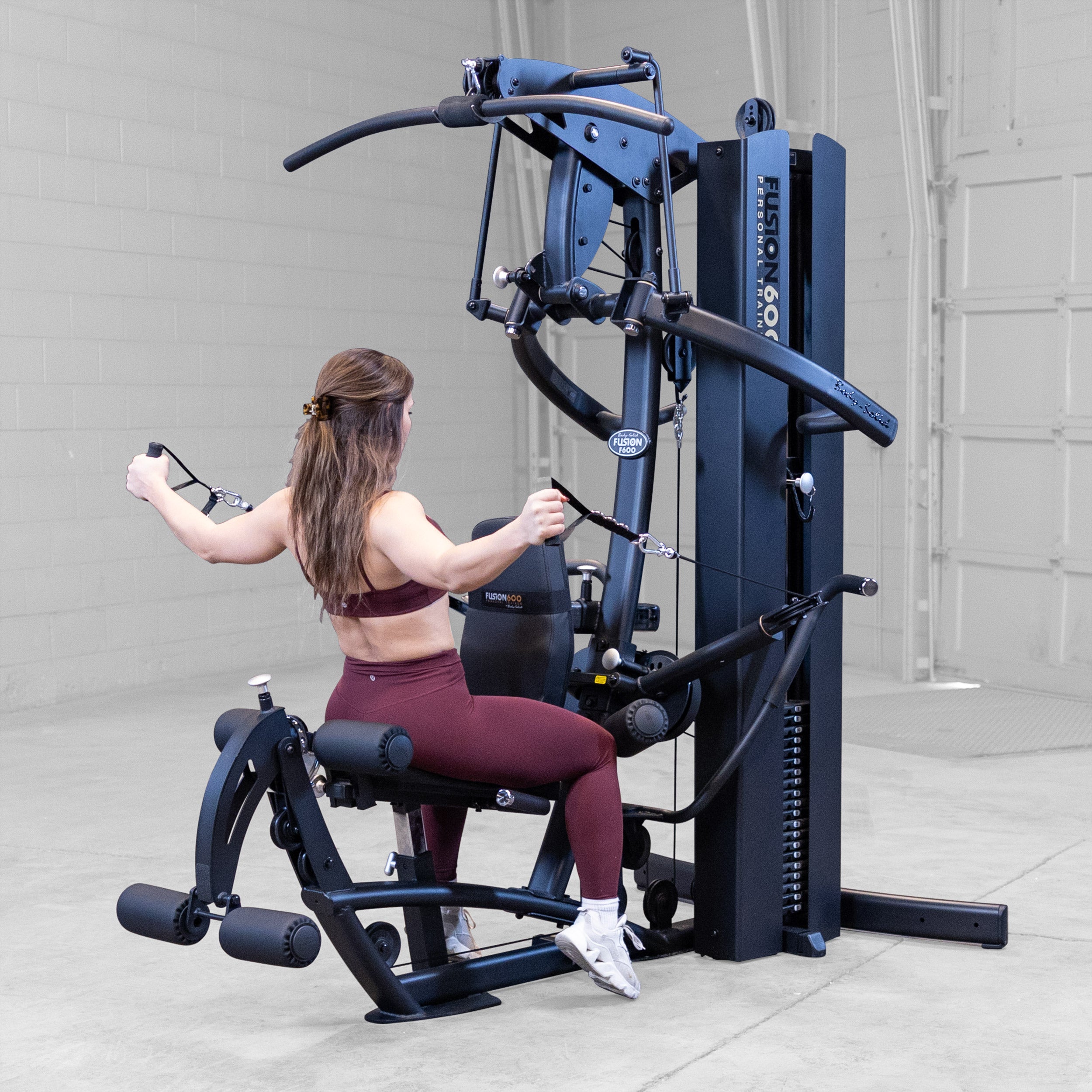 Woman performing a seated reverse fly on the Body-Solid Fusion 600B Personal Trainer using the functional training arms
