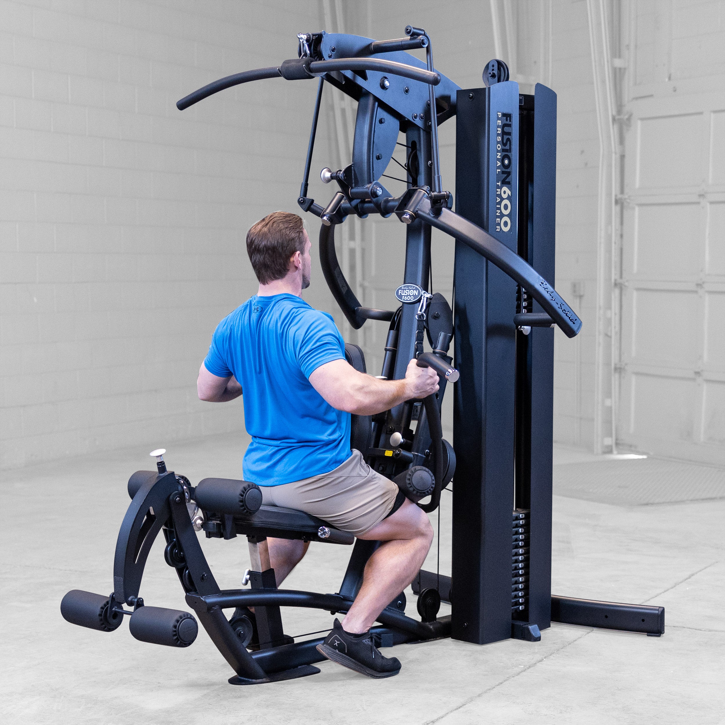 Man performing a seated row on the Body-Solid Fusion 600B Personal Trainer using the functional training arms