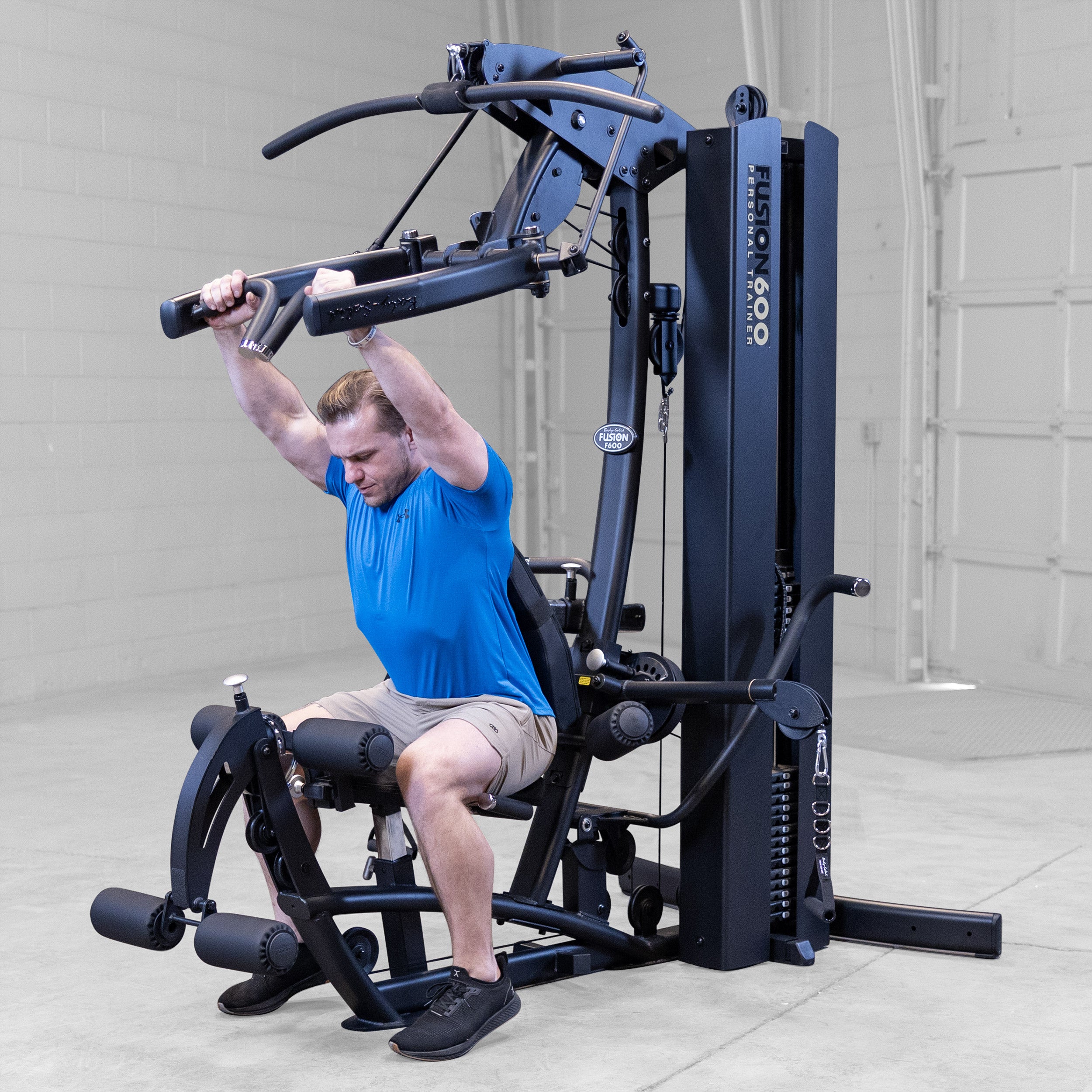 Man performing a seated shoulder press on the Body-Solid Fusion 600B Personal Trainer using the Bi-Angular Press Arms