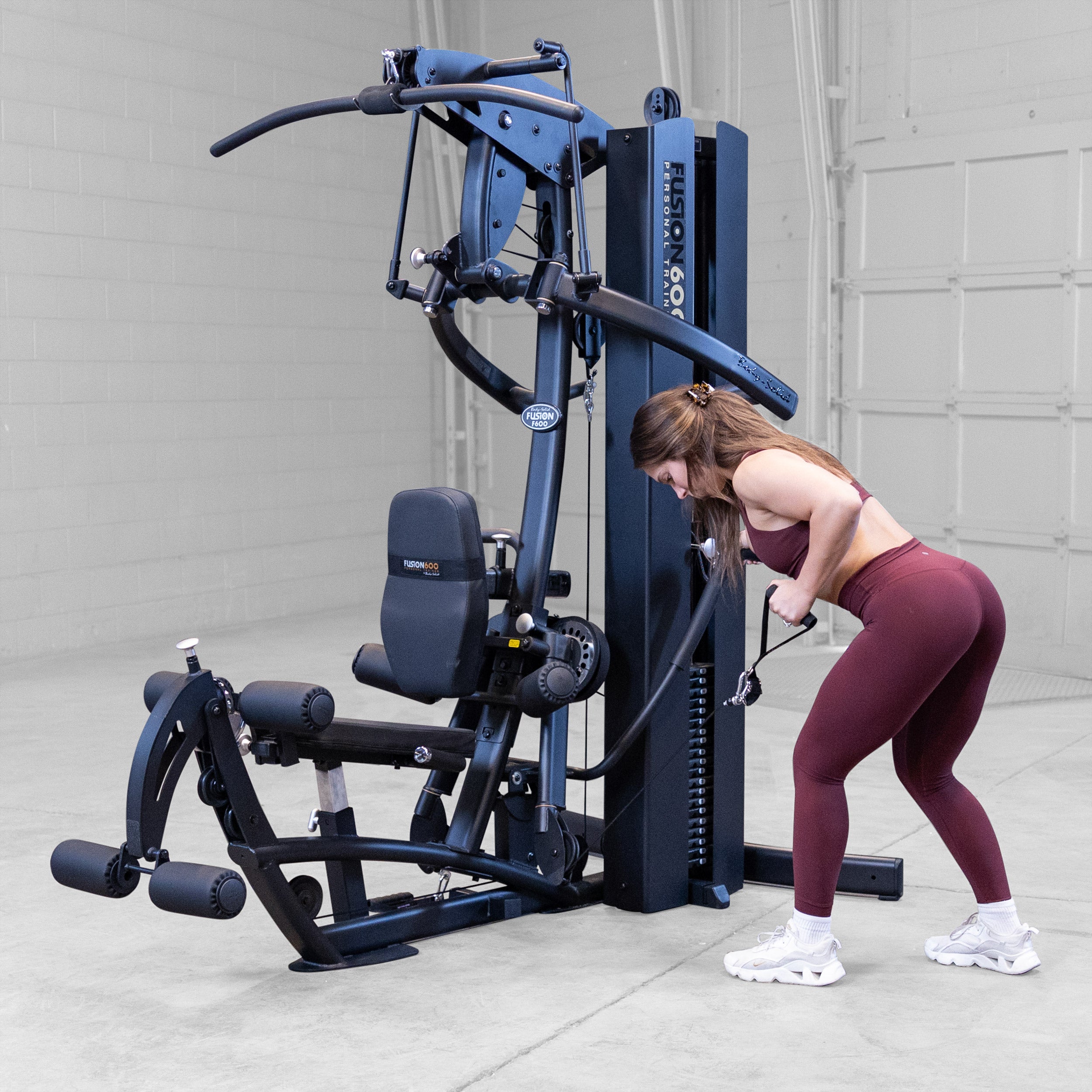 Woman performing a standing single arm row on the Body-Solid Fusion 600B Personal Trainer using the functional training handle