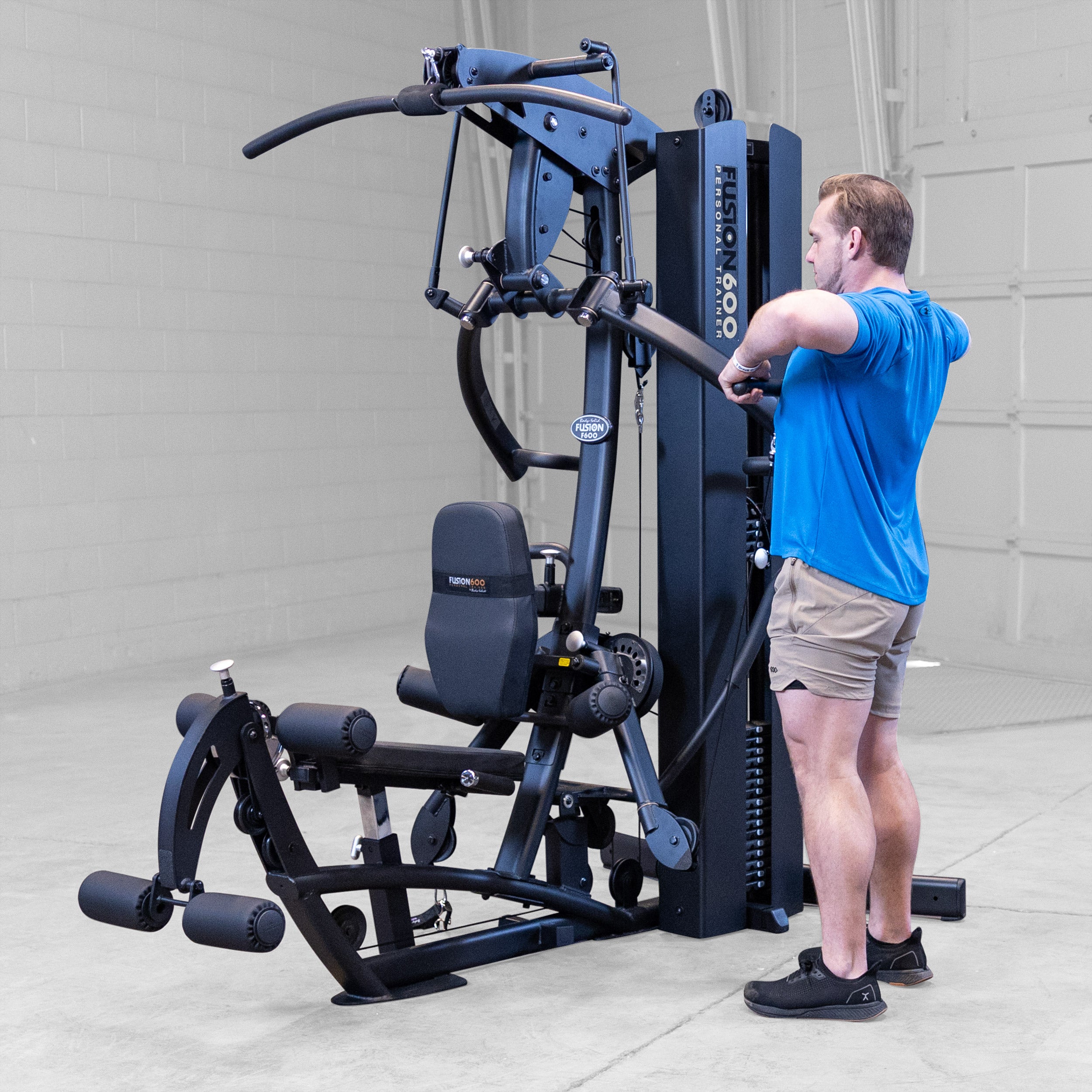 Man performing a standing upright row on the Body-Solid Fusion 600B Personal Trainer using a straight bar attachment